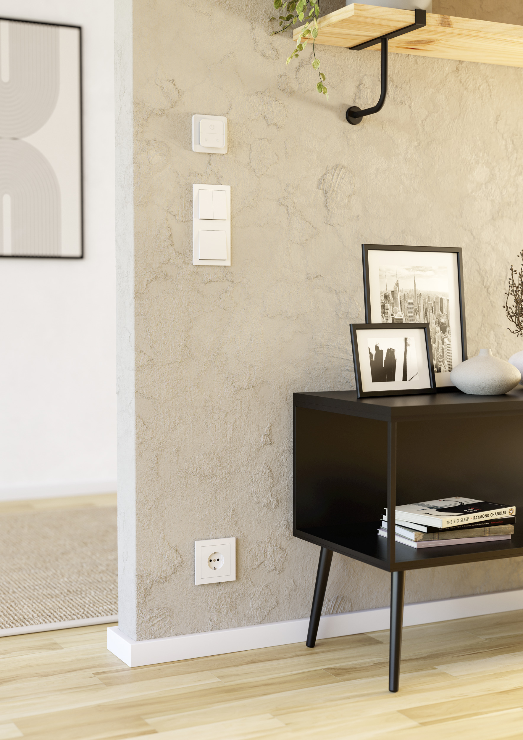 Angolo del soggiorno con interruttori a muro, arte e mobile nero con libri. Pavimento in legno, parete beige e vista di un'altra stanza.