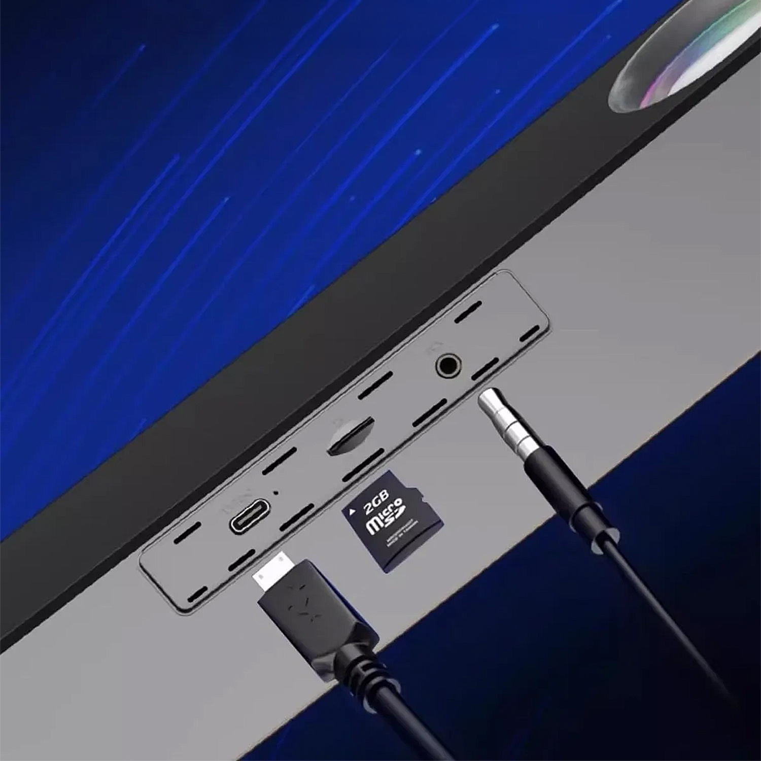 Primo piano delle porte di un dispositivo con cavo USB, jack da 3,5 mm e scheda micro SD. Lo sfondo mostra uno schermo blu.