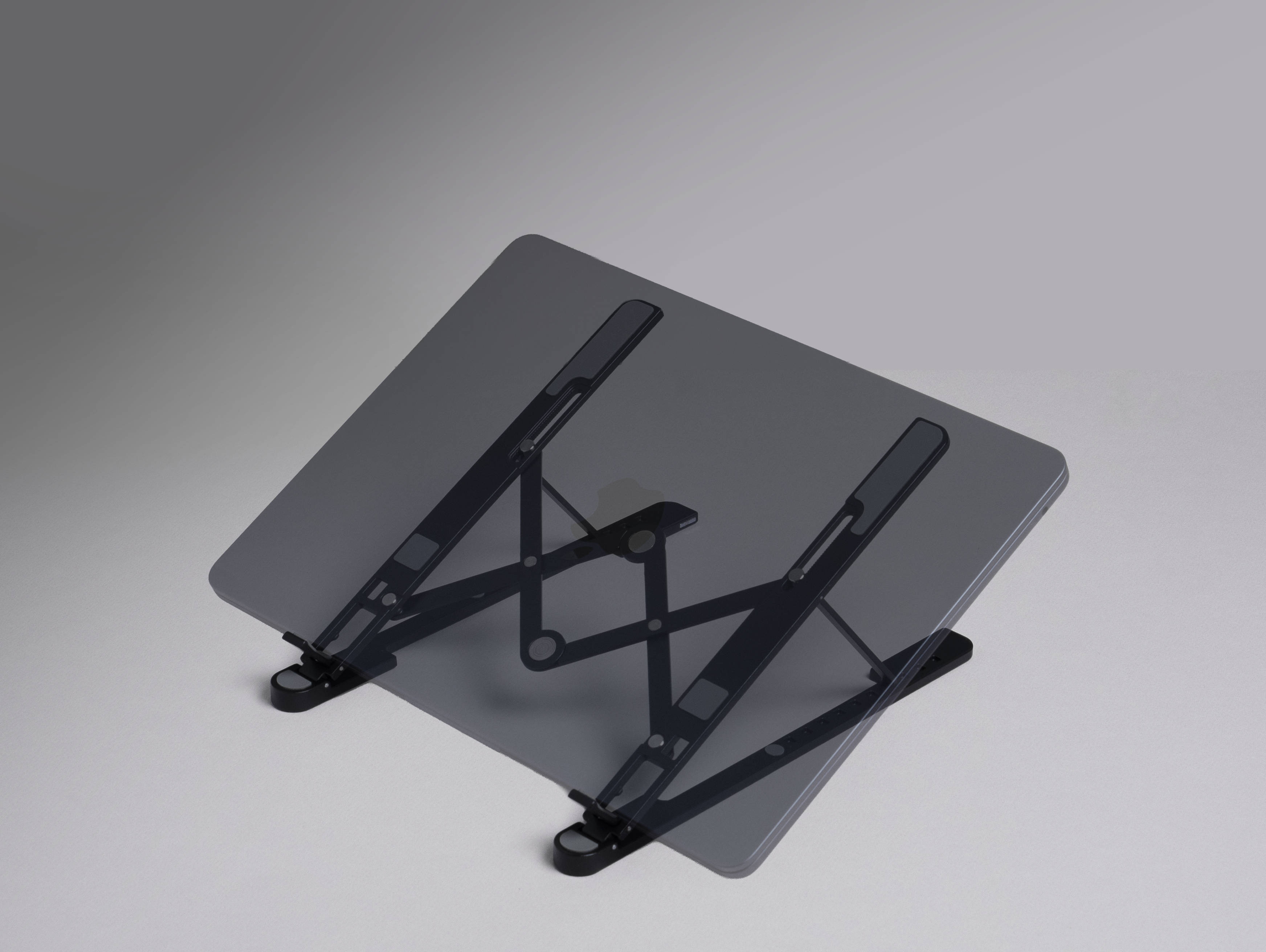 Ein grauer Laptop-Ständer wird auf grauem Hintergrund gezeigt. Er ist abgewinkelt und unterstützt einen dunkelgrauen Laptop.
