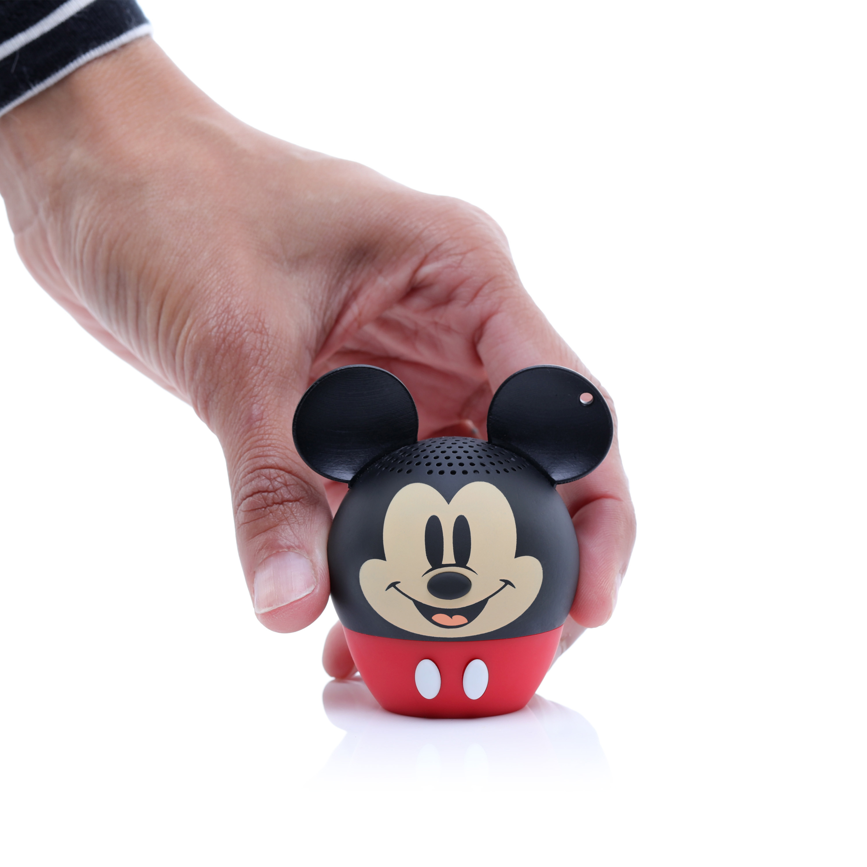 Una mano tiene in mano un altoparlante a forma di Mickey Mouse. È nero, rosso e beige, con sfondo bianco.