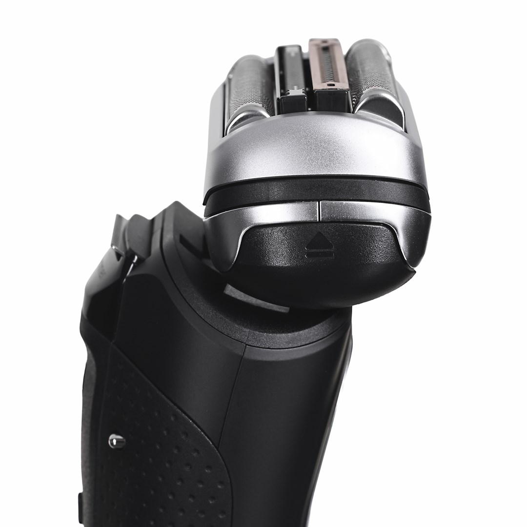 Zbliżenie czarno-srebrnej golarki elektrycznej. Głowica golarki jest srebrna, z czarną podstawą. Uchwyt jest czarny.