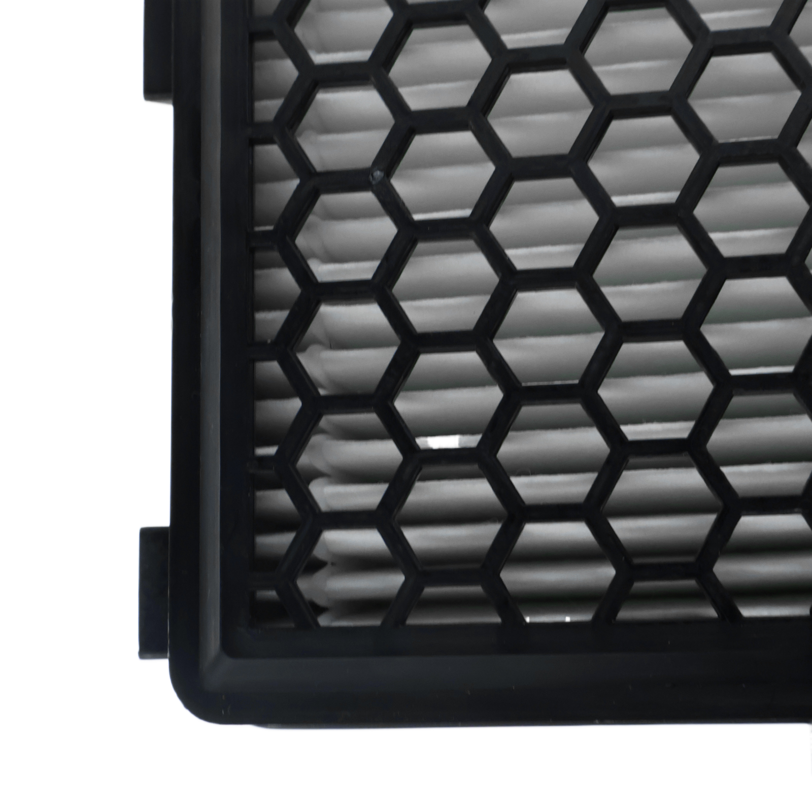Nahaufnahme eines schwarzen Luftfilters mit Wabenmuster. Gefiltertes Material hinter dem Gitter sichtbar.