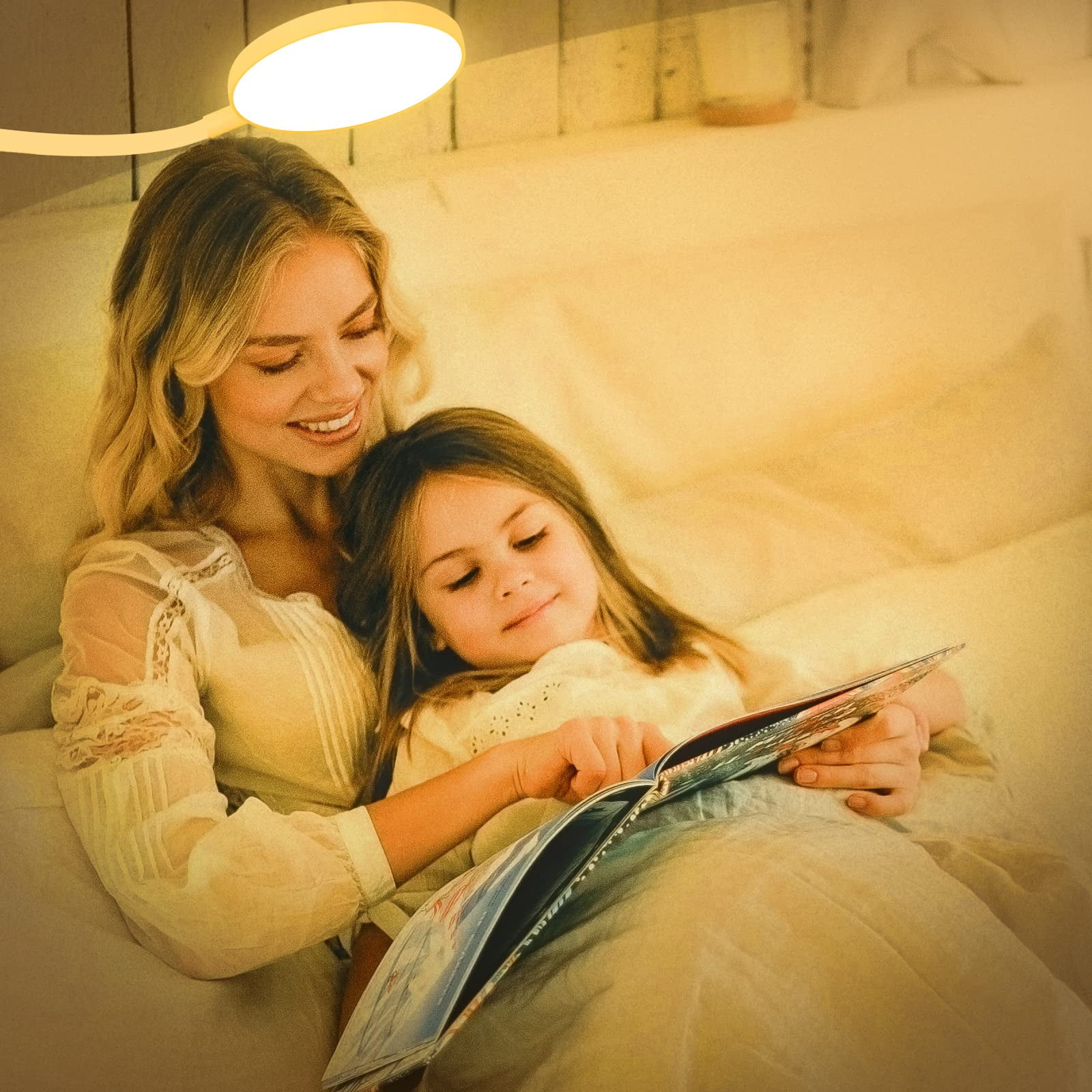 Eine Frau und ein Mädchen lesen gemeinsam im Bett unter sanftem Licht ein Buch. Die Frau lächelt und das Mädchen schaut ins Buch.