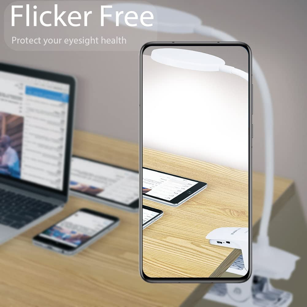 Ein Schreibtisch mit Laptop, Tablet und Telefon. Eine weiße Lampe ist am Schreibtisch befestigt. Das Bild wird von einem Telefon gerahmt.