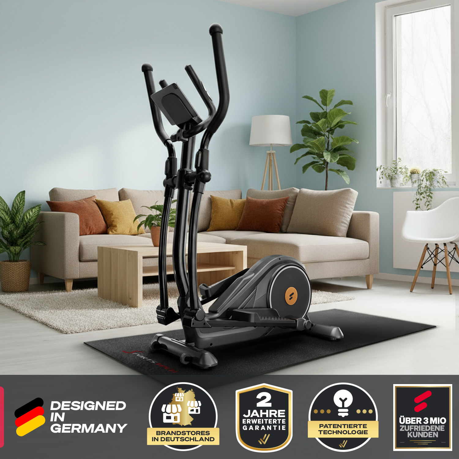 Schwarzer Crosstrainer auf einer schwarzen Matte in einem Wohnzimmer. Sofa, Pflanzen und Fenster im Hintergrund sichtbar.