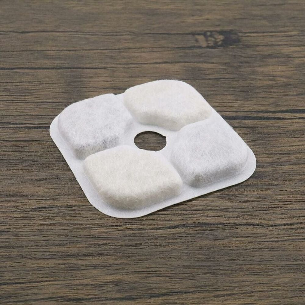 Ein weißer Filter mit vier weißen Pads und einem zentralen Loch auf einer Holzoberfläche.