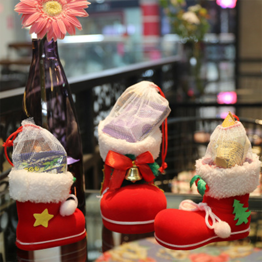 Rote, stiefelförmige Weihnachtsschmuckstücke mit weißem Pelzbesatz, die Geschenke halten. Eine rosa Blume und eine lila Vase sind im Hintergrund.