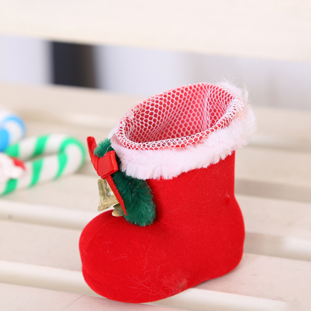 Ein roter Weihnachtsstrumpf mit weißem Fellbesatz und einem Netzoberteil. Ein kleiner Bogen und eine Glocke sind befestigt.  Zuckerstangen im Hintergrund.