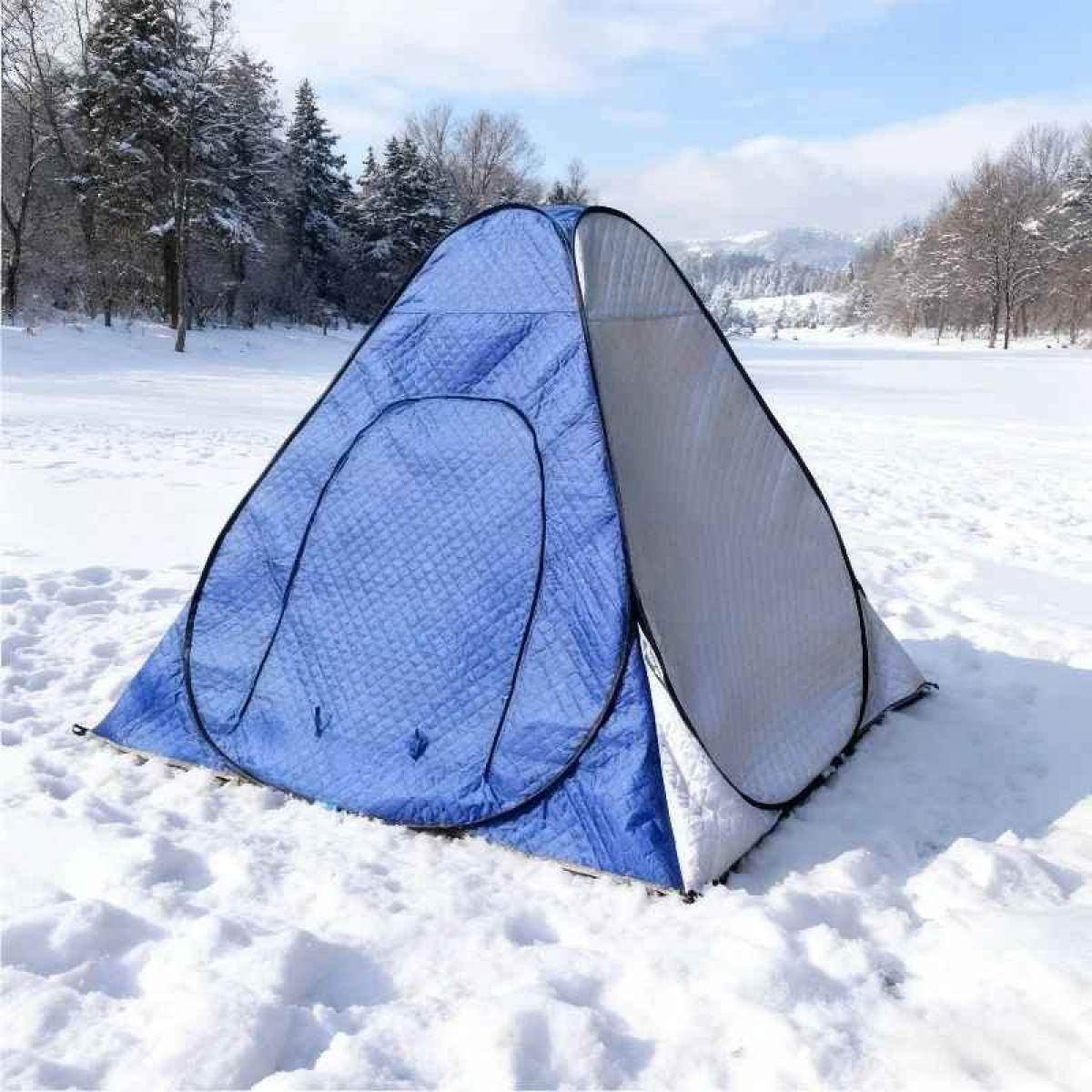 Ein blau-weißes Zelt steht in einer verschneiten Landschaft. Bäume und Berge sind im Hintergrund unter blauem Himmel.