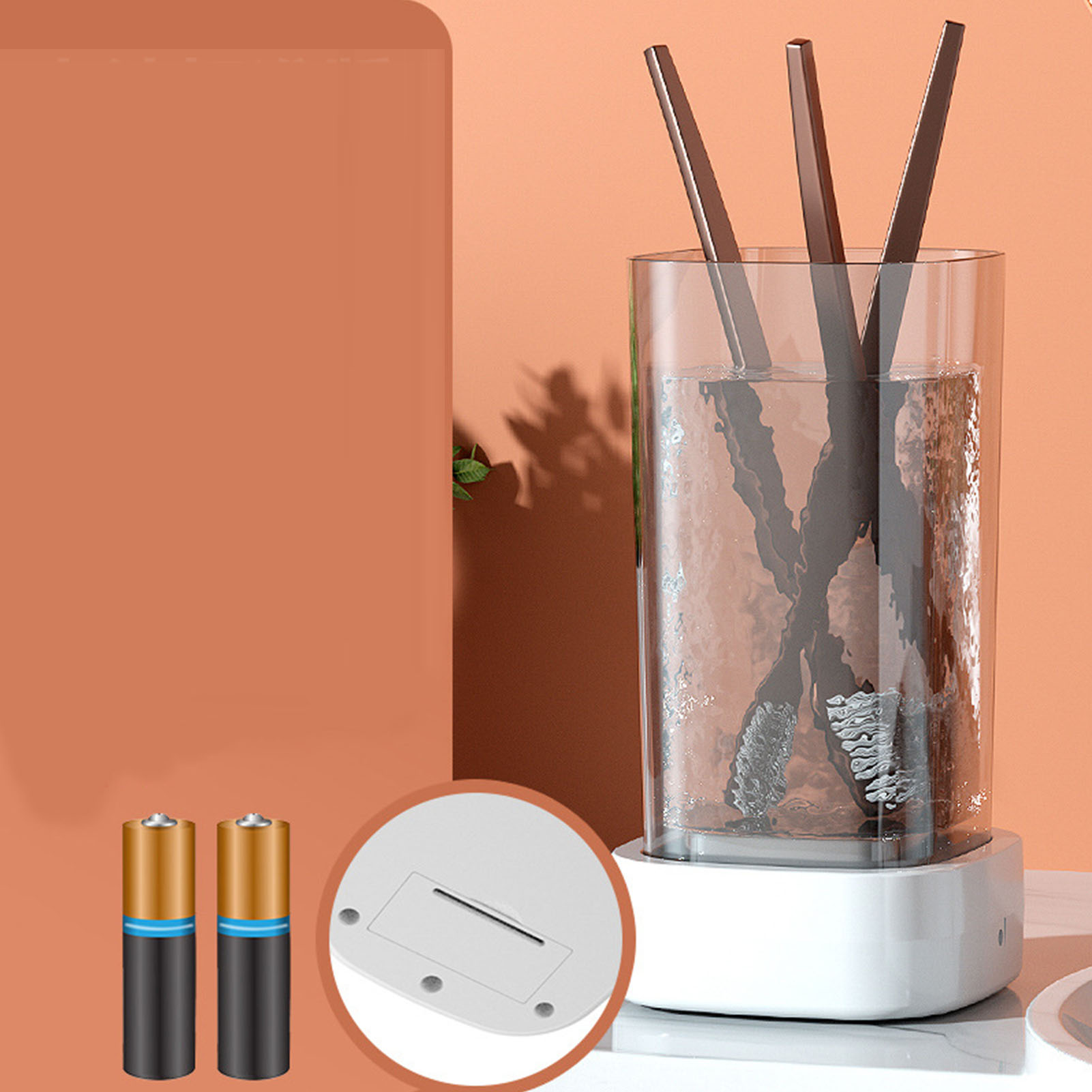 Das Bild zeigt ein Glas mit Reinigungsbürsten, Batterien und einer weißen Basis. Der Hintergrund ist orange.