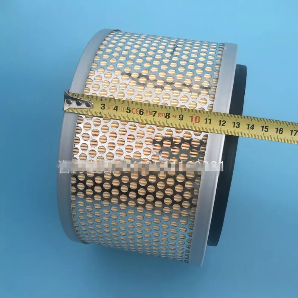 Ein Luftfilter wird mit einem Maßband gemessen. Er ist zylindrisch, mit einem perforierten Metallgehäuse und einem beigefarbenen Filter im Inneren, auf blauem Hintergrund.