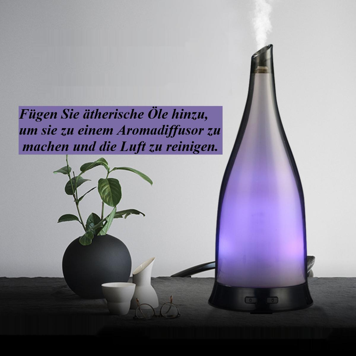 Ein Aromatherapie-Diffusor mit lila Licht und Dampf. Eine Pflanze, kleine Vasen und Gläser stehen auf einem Tisch. Deutscher Text.