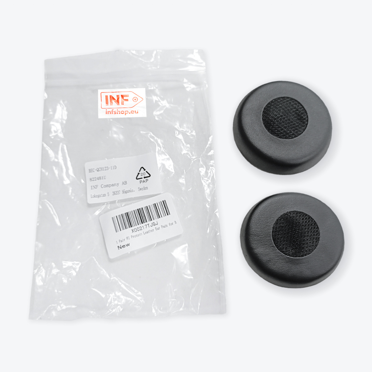 Dwie czarne wkładki do uszu z siatkowymi środkami i plastikowa torba z informacjami o produkcie na białej powierzchni.