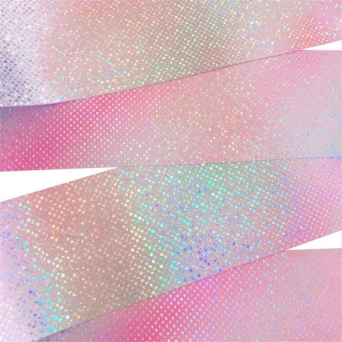 Nahaufnahme von drei Bändern mit schillernden, punkttexturierten Oberflächen. Die Farben reichen von Rosa bis Weiß, mit einem Hauch von Blau und Grün.