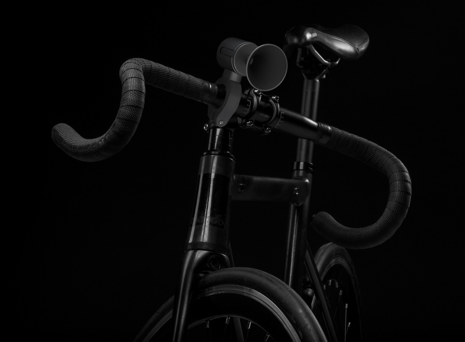 Black bicycle frame with curved handlebars, a seat, and wheels. A horn-like device is mounted on the handlebars.