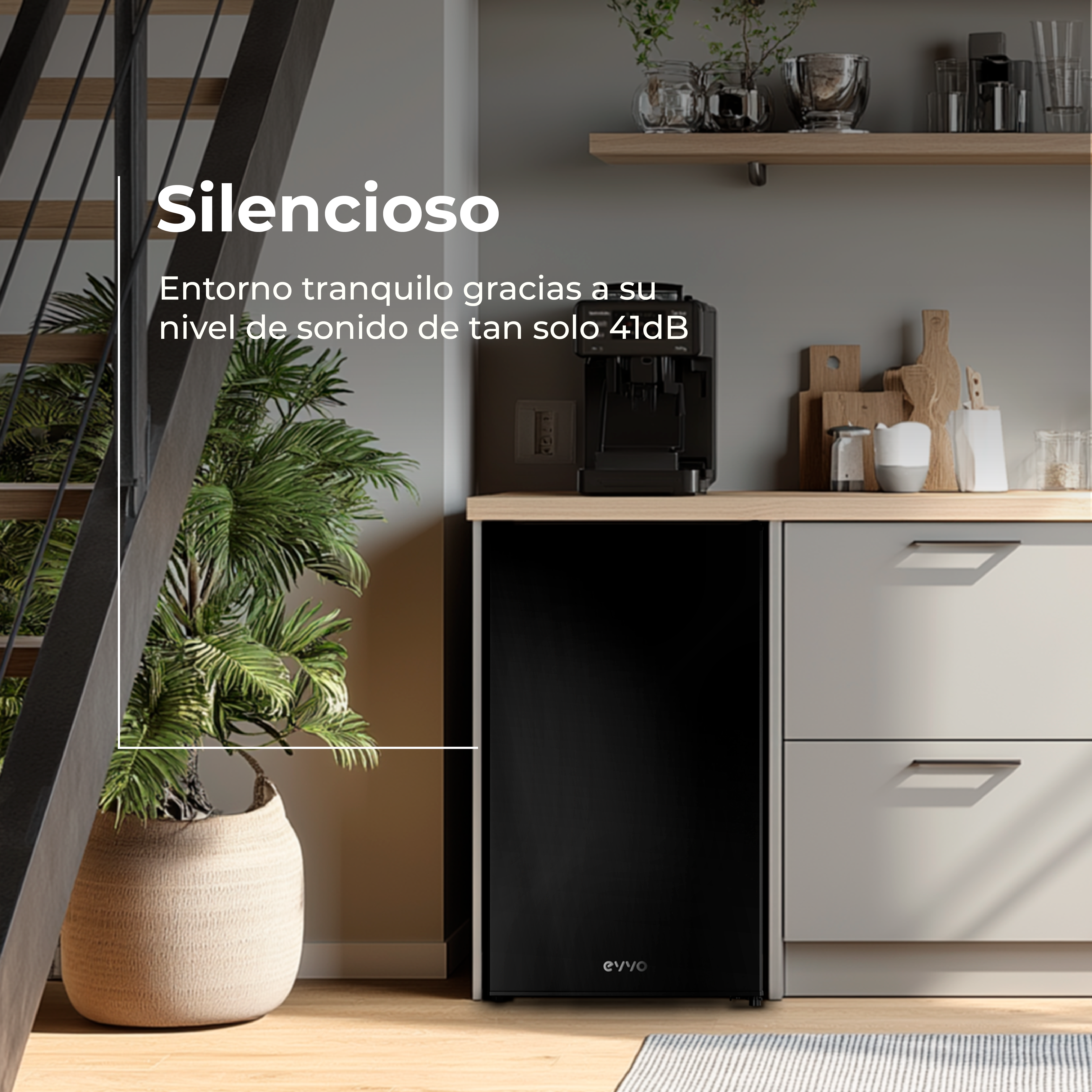 Una escena de cocina con un refrigerador negro. Una planta en maceta está junto a una escalera.