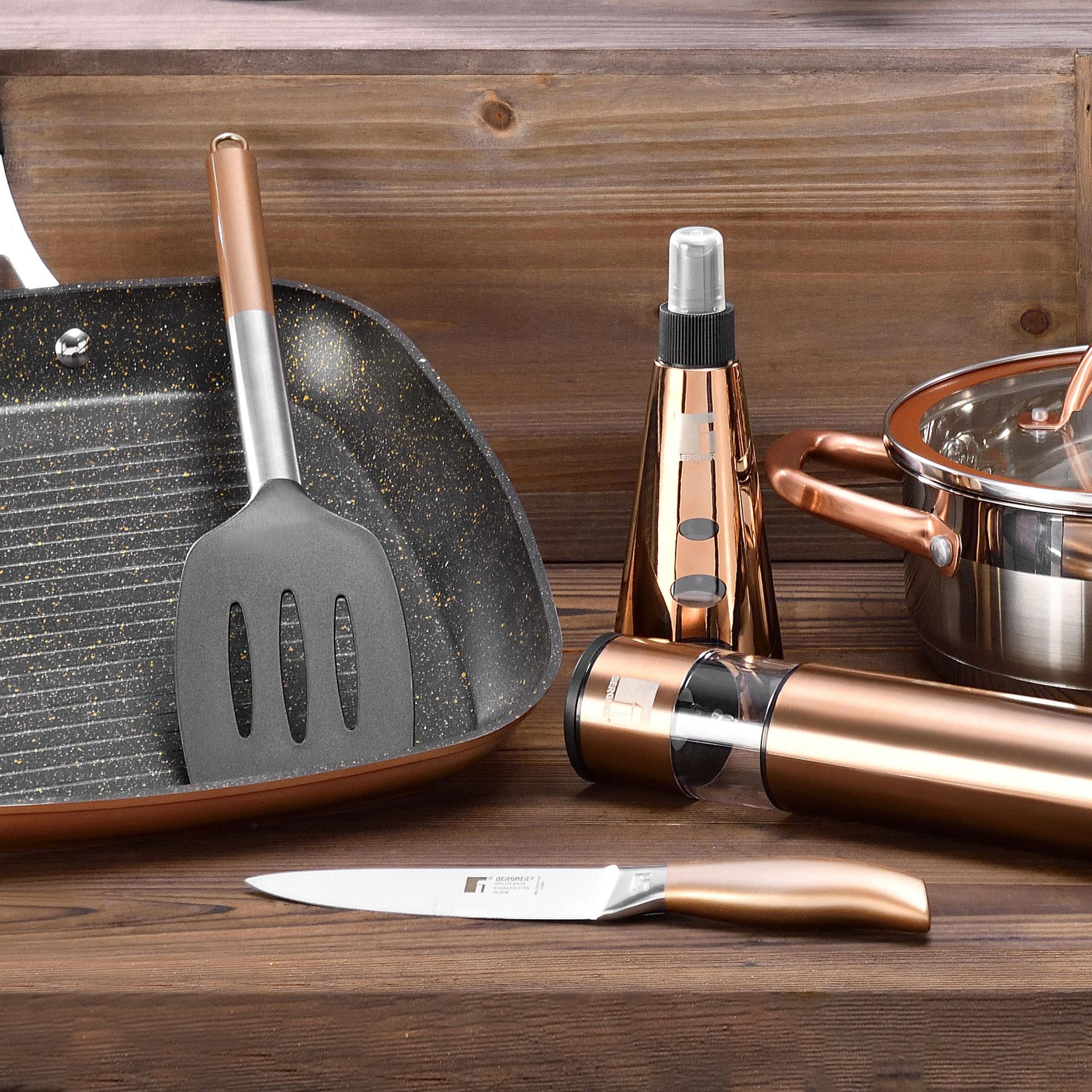 Utensilios de cocina sobre superficie de madera: sartén, espátula, cuchillo, saleros y pimenteros y olla.