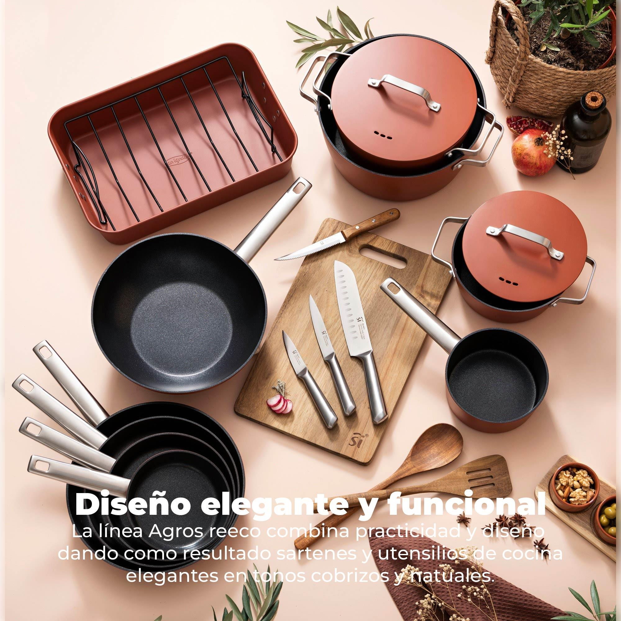 Juego de utensilios de cocina sobre una superficie rosa. Incluye sartenes, ollas, cuchillos, tabla de cortar, cesta y elementos.