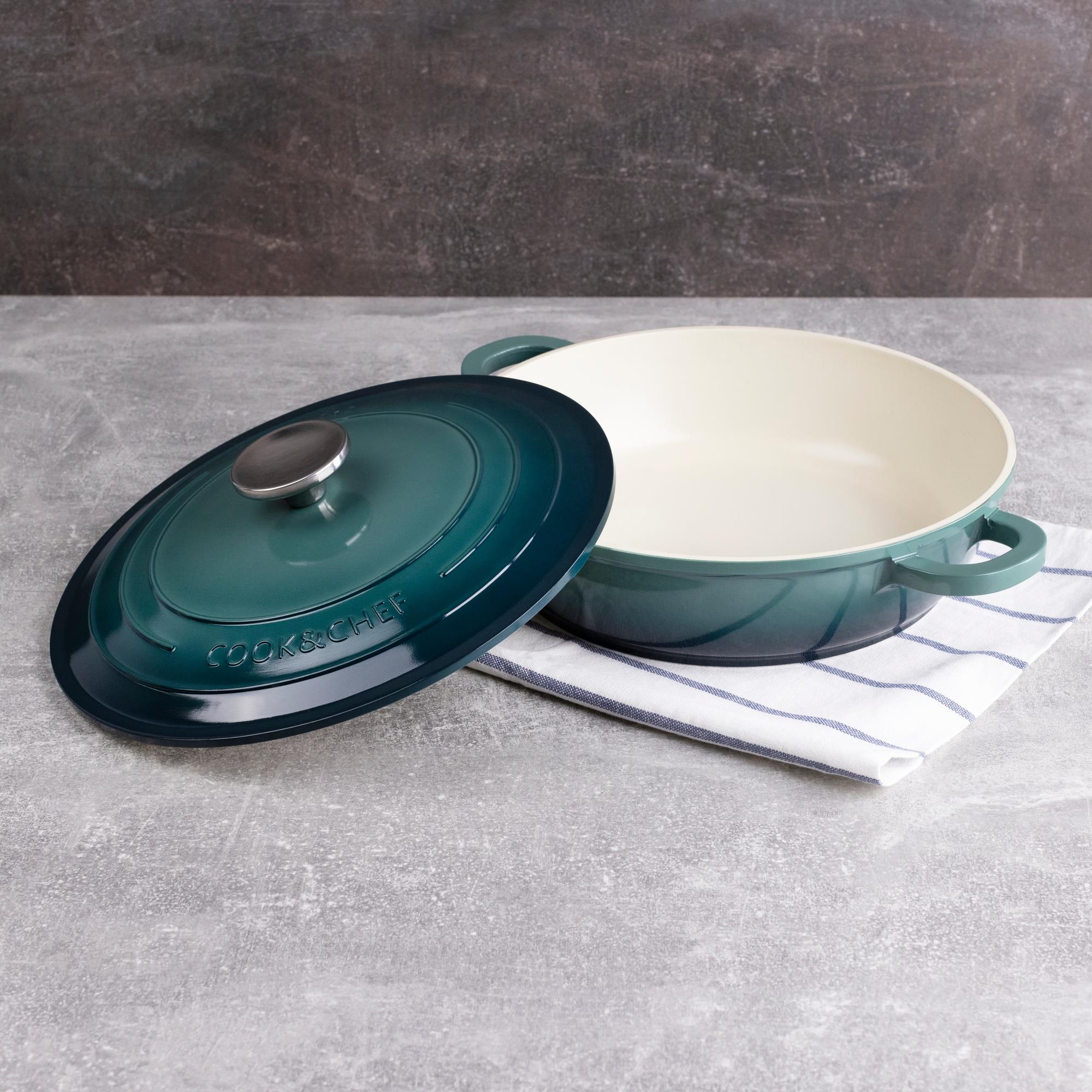 Una olla Cook & Chef verde azulado con tapa quitada. Está sobre un paño a rayas en una superficie gris.