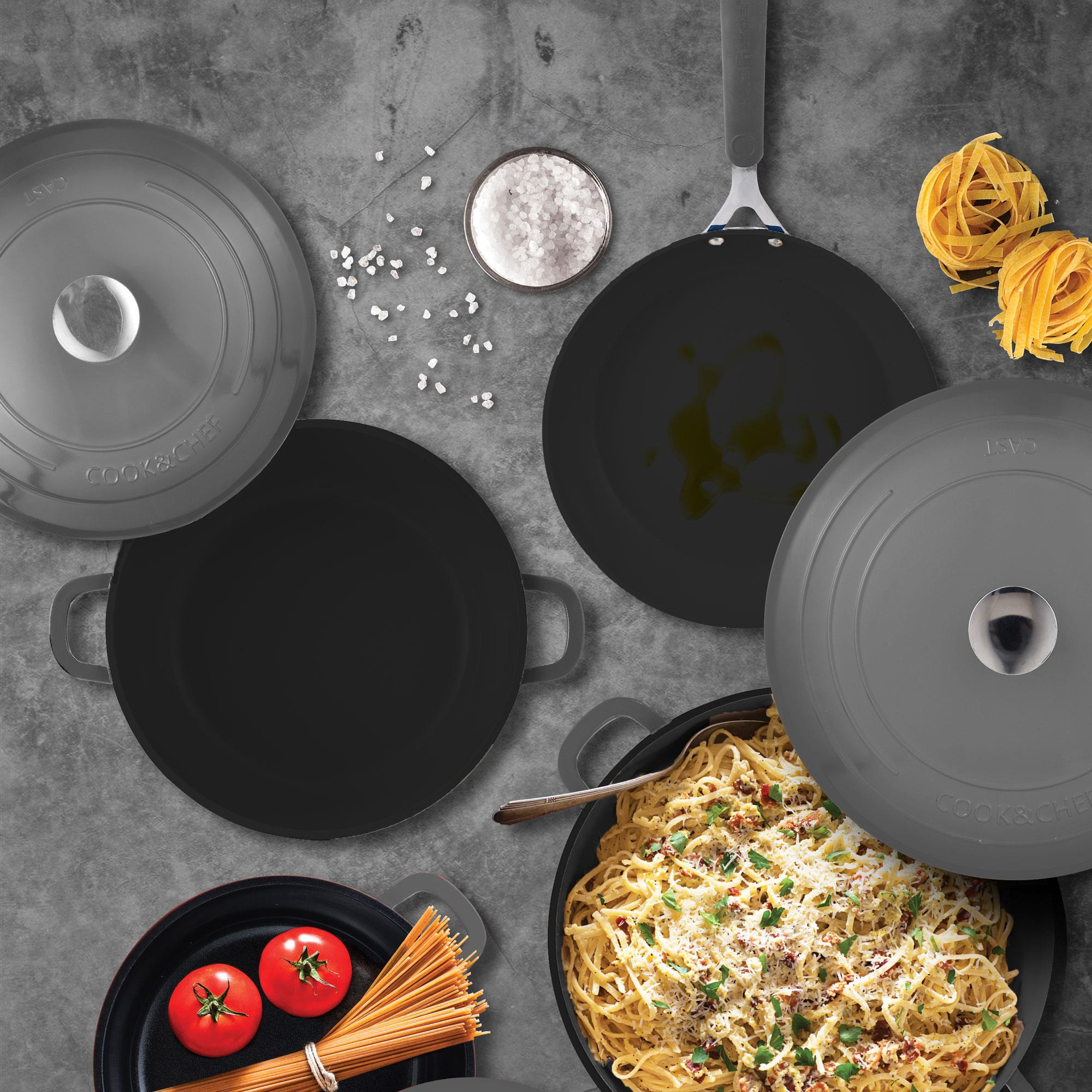 Vista cenital de varios utensilios de cocina, pasta, tomates y sal sobre una superficie gris, lo que sugiere una escena de cocina.