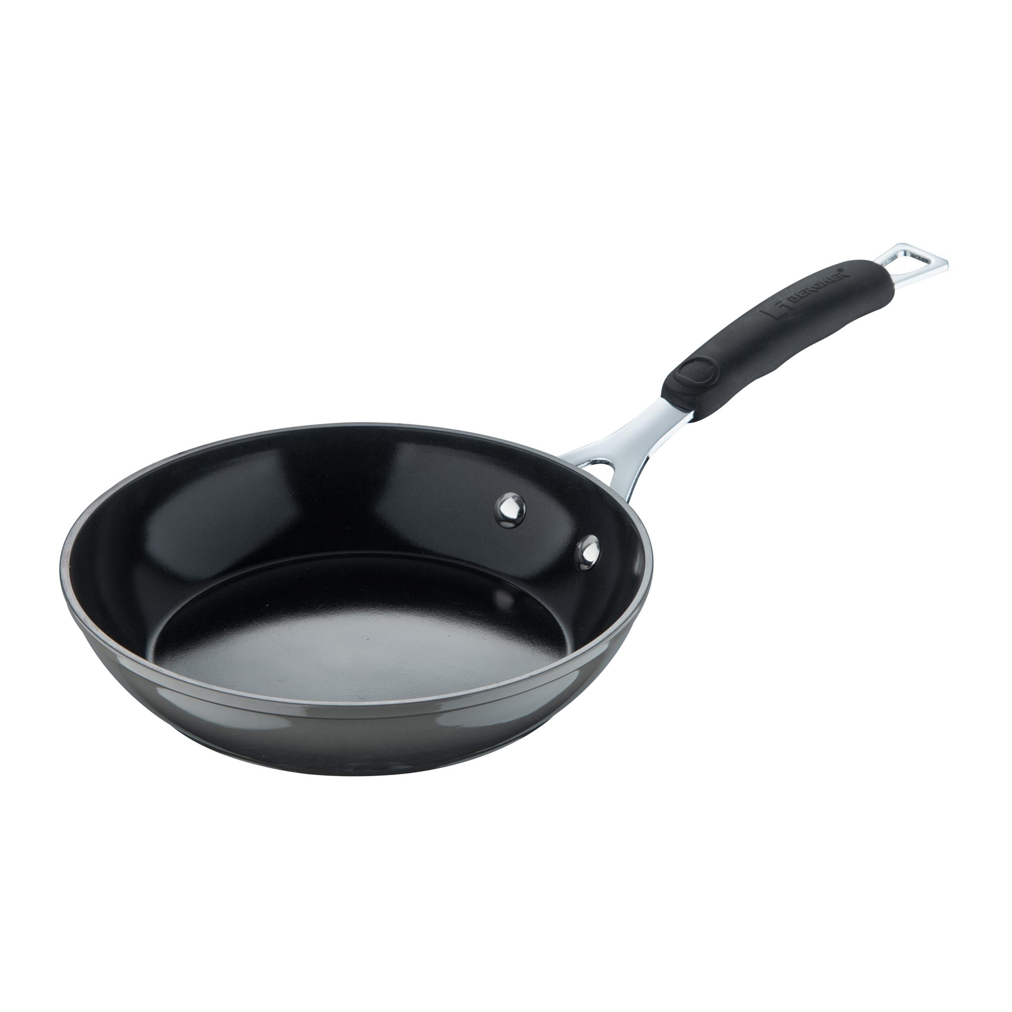 Una sartén negra con mango largo. El mango es negro con un accesorio plateado. La sartén tiene un borde plateado.
