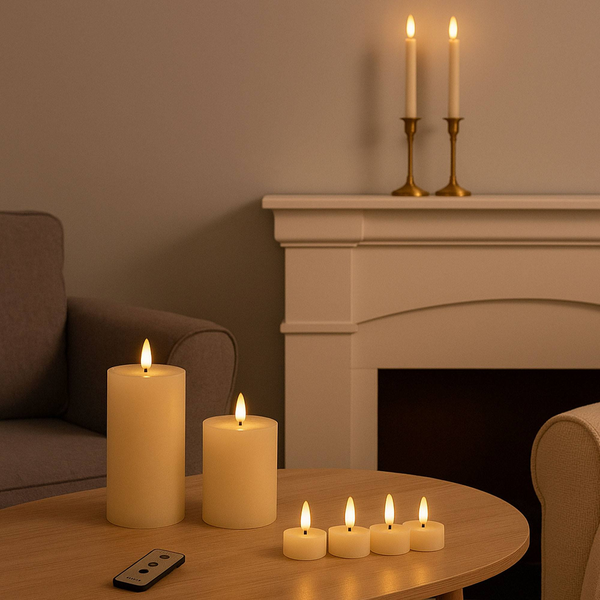 Velas encendidas sobre una mesa frente a una chimenea. También hay un mando a distancia y dos sillones.