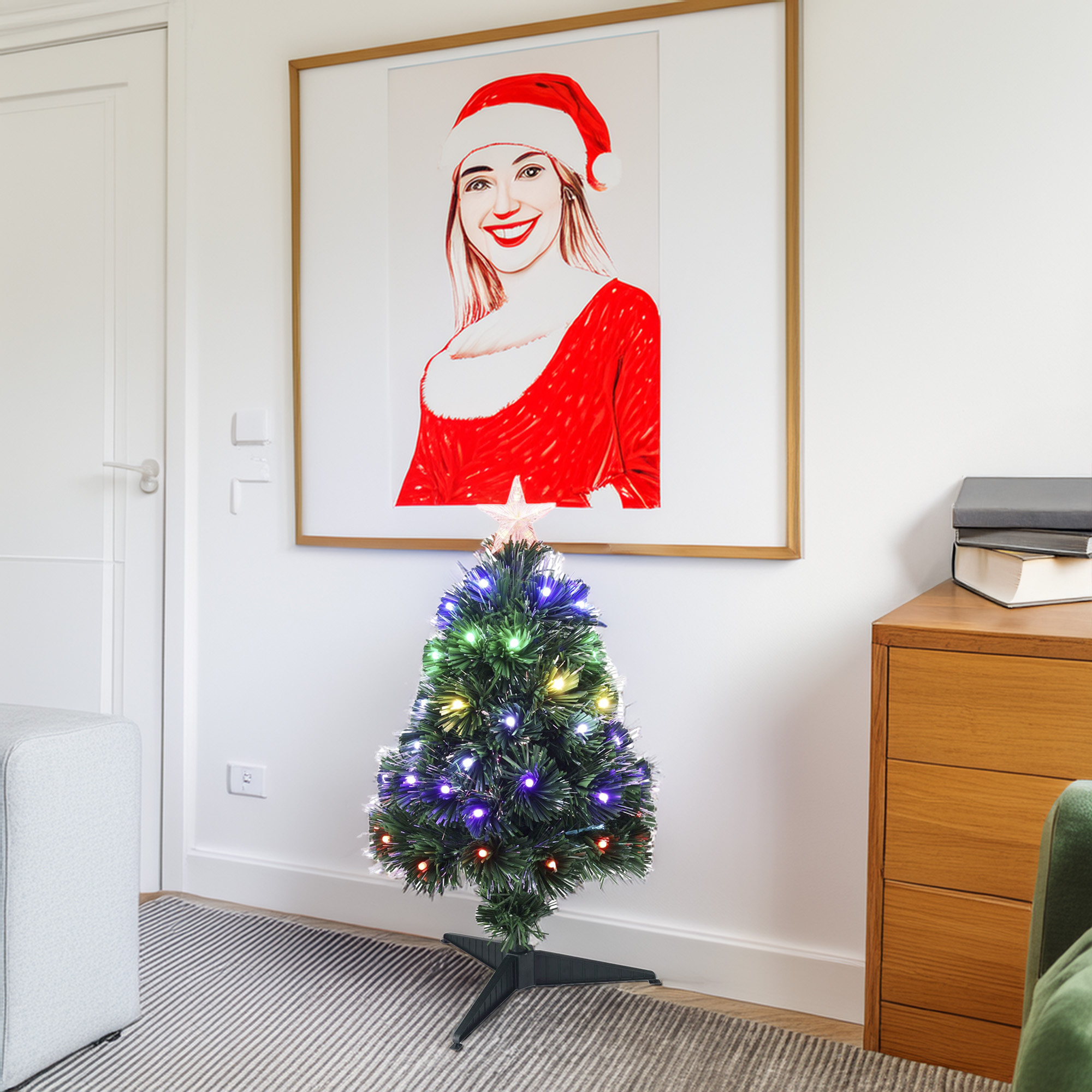 Una habitación con un árbol de Navidad y una imagen enmarcada de una mujer con un traje de Papá Noel. Un armario y un sofá gris son visibles.