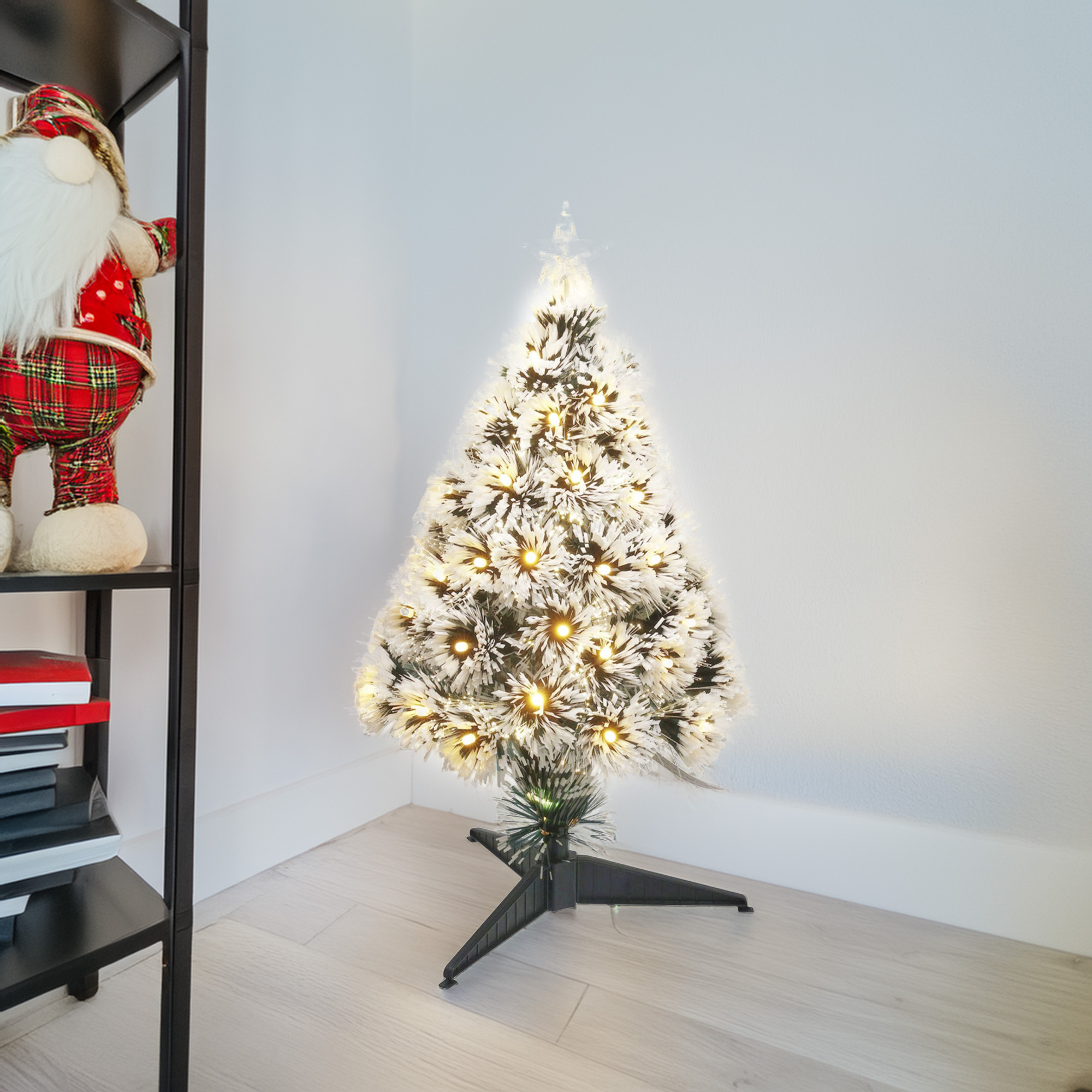 Un árbol de Navidad iluminado está en una esquina. Una decoración de Papá Noel y libros están en un estante. El suelo es de madera clara.