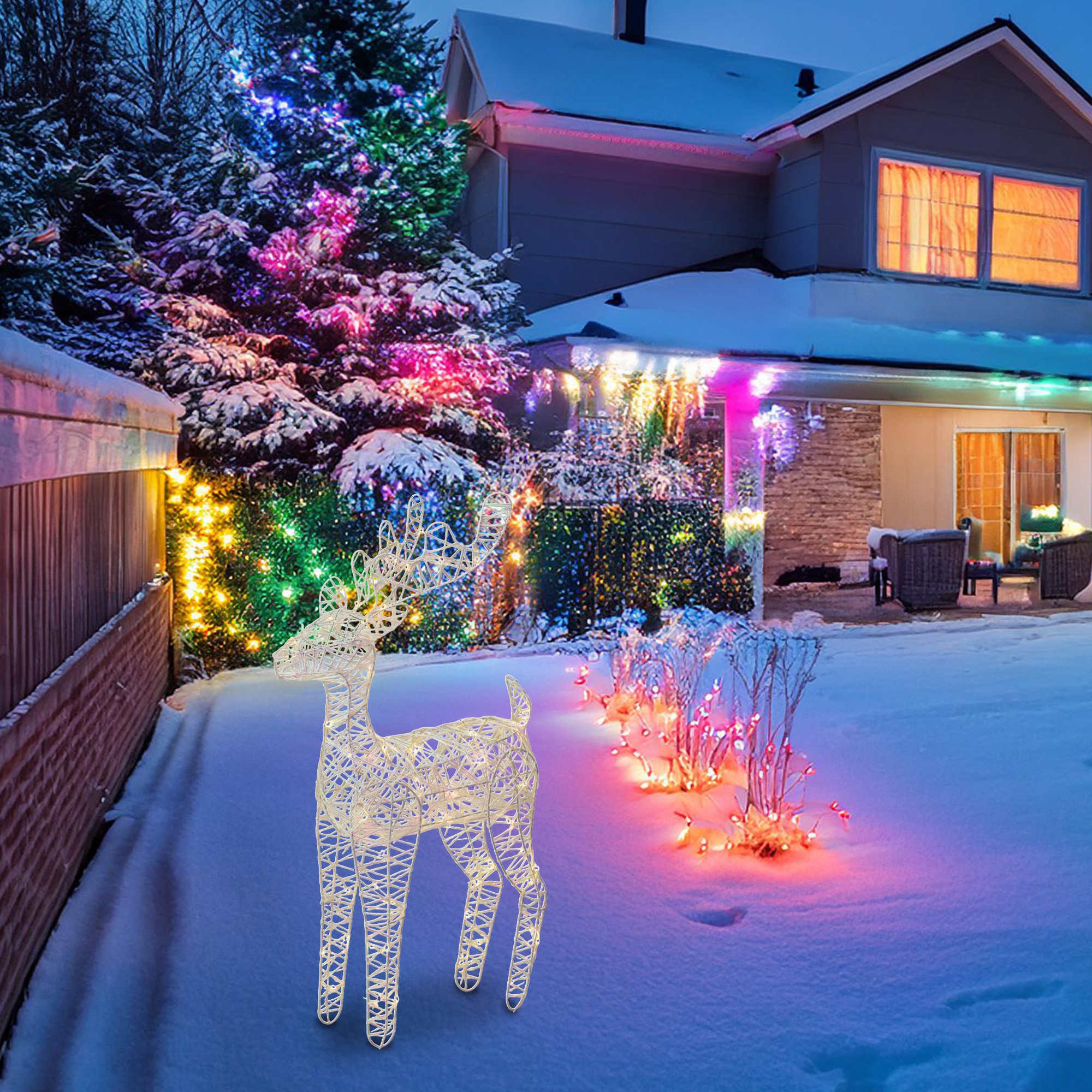 Una casa con luces navideñas y una decoración de ciervo en el patio nevado. La casa tiene ventanas cálidamente iluminadas.