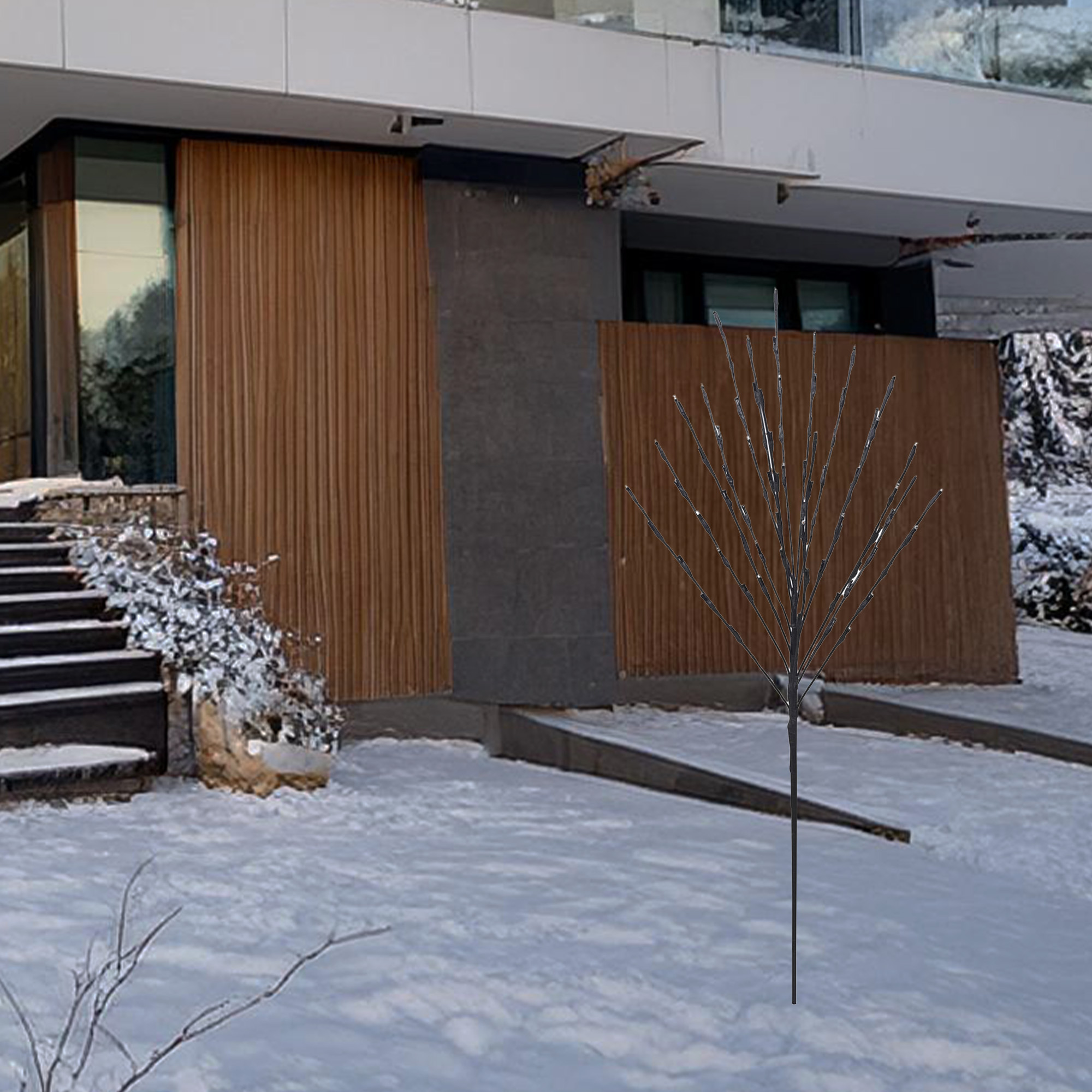 Un edificio moderno con paneles de madera. Un árbol decorativo en el jardín nevado. Escaleras a la entrada.