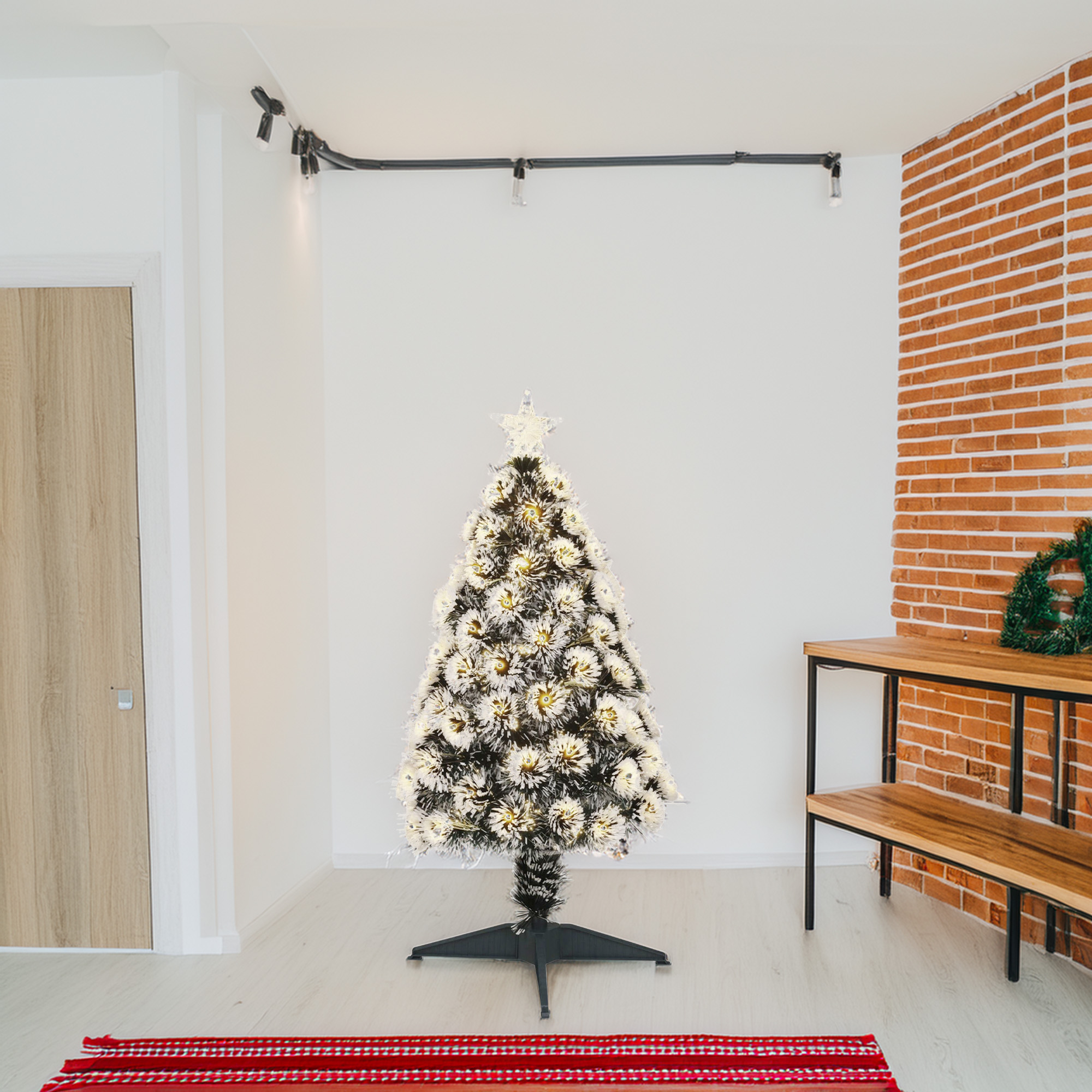Un árbol de Navidad decorado está en una habitación con paredes blancas, una pared de ladrillo y un banco de madera. Se ve una alfombra roja.