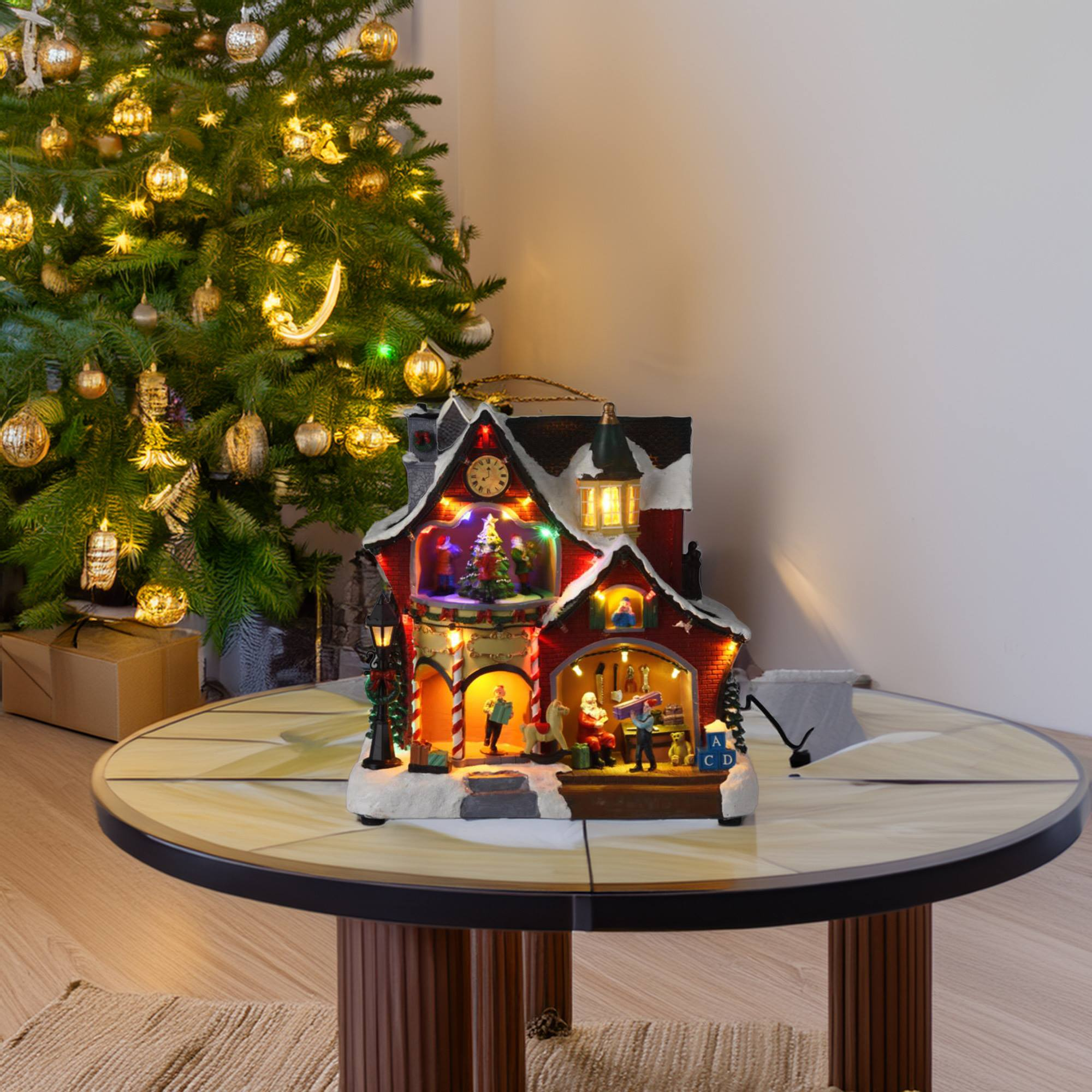 Una escena de pueblo navideño en una mesa, con un árbol iluminado y adornos en el fondo.
