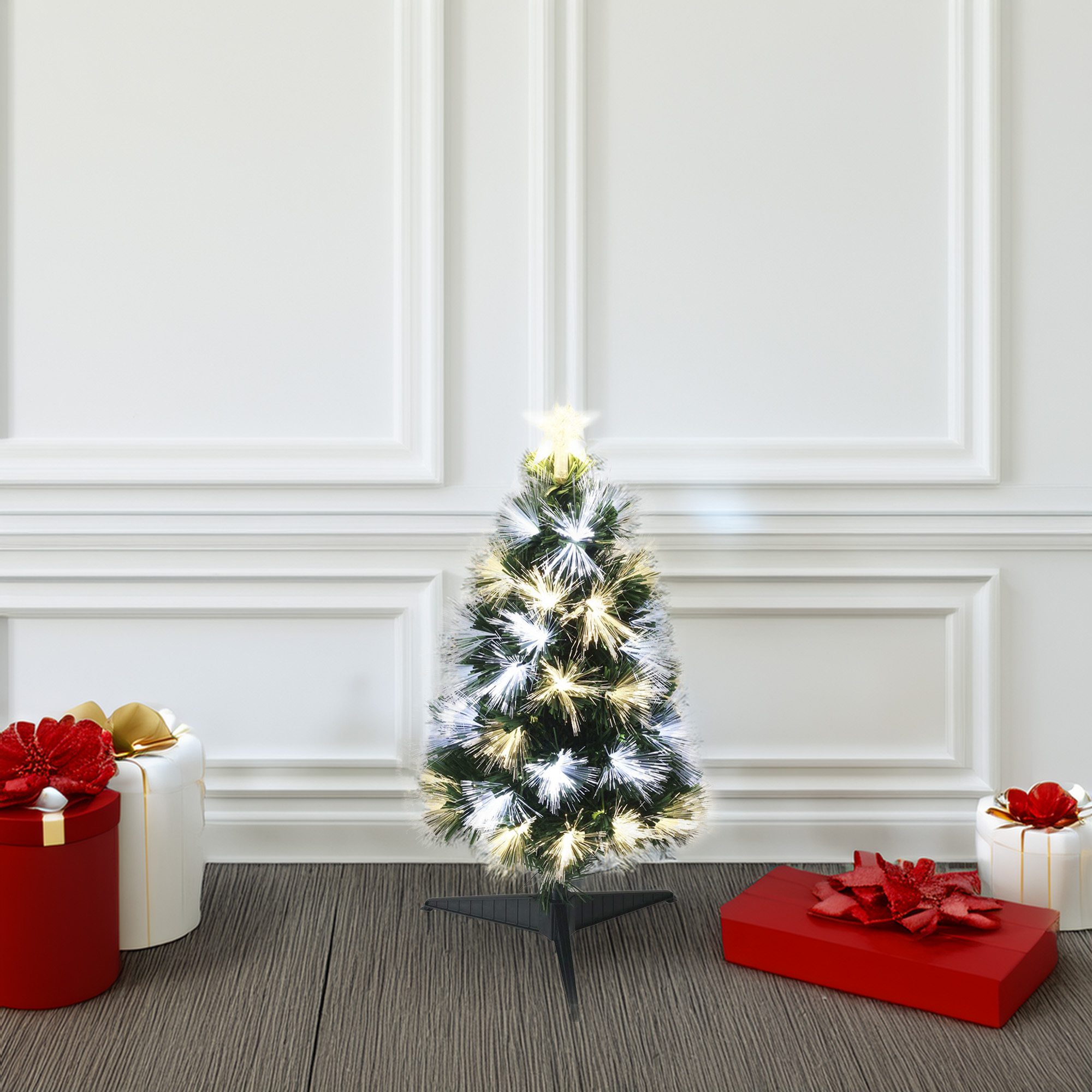 Árbol de Navidad con luces y estrella, regalos en el suelo.
