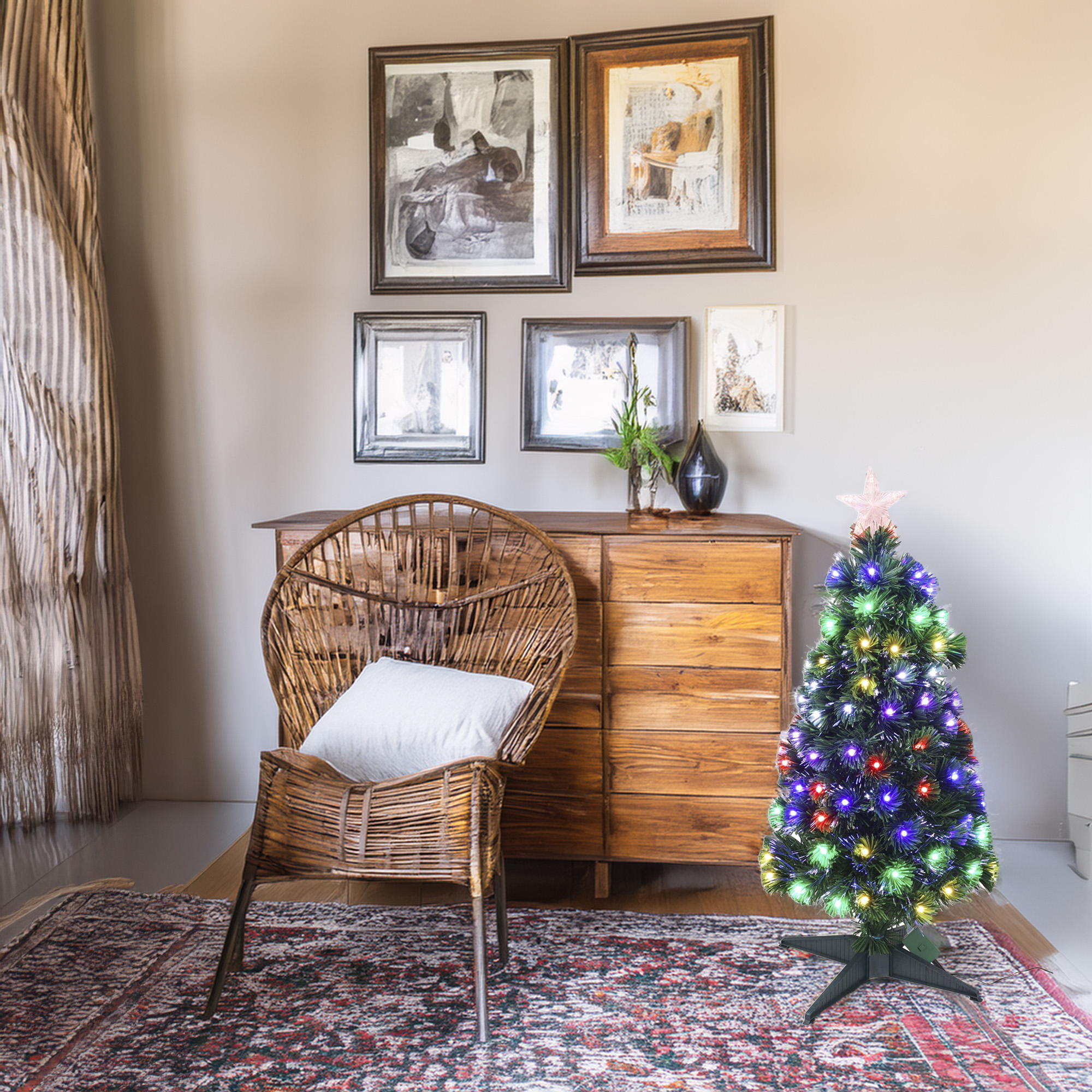 Una habitación con una silla de mimbre, una cómoda de madera, arte y un pequeño árbol de Navidad con luces de colores.
