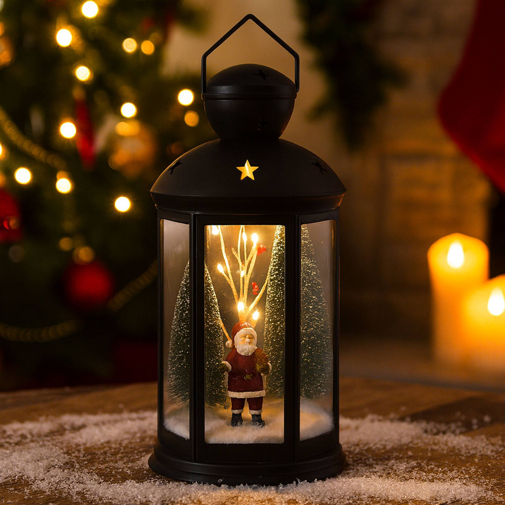 Una linterna negra con una figura de Papá Noel dentro. Un árbol de Navidad y velas están en el fondo. Nieve al frente.