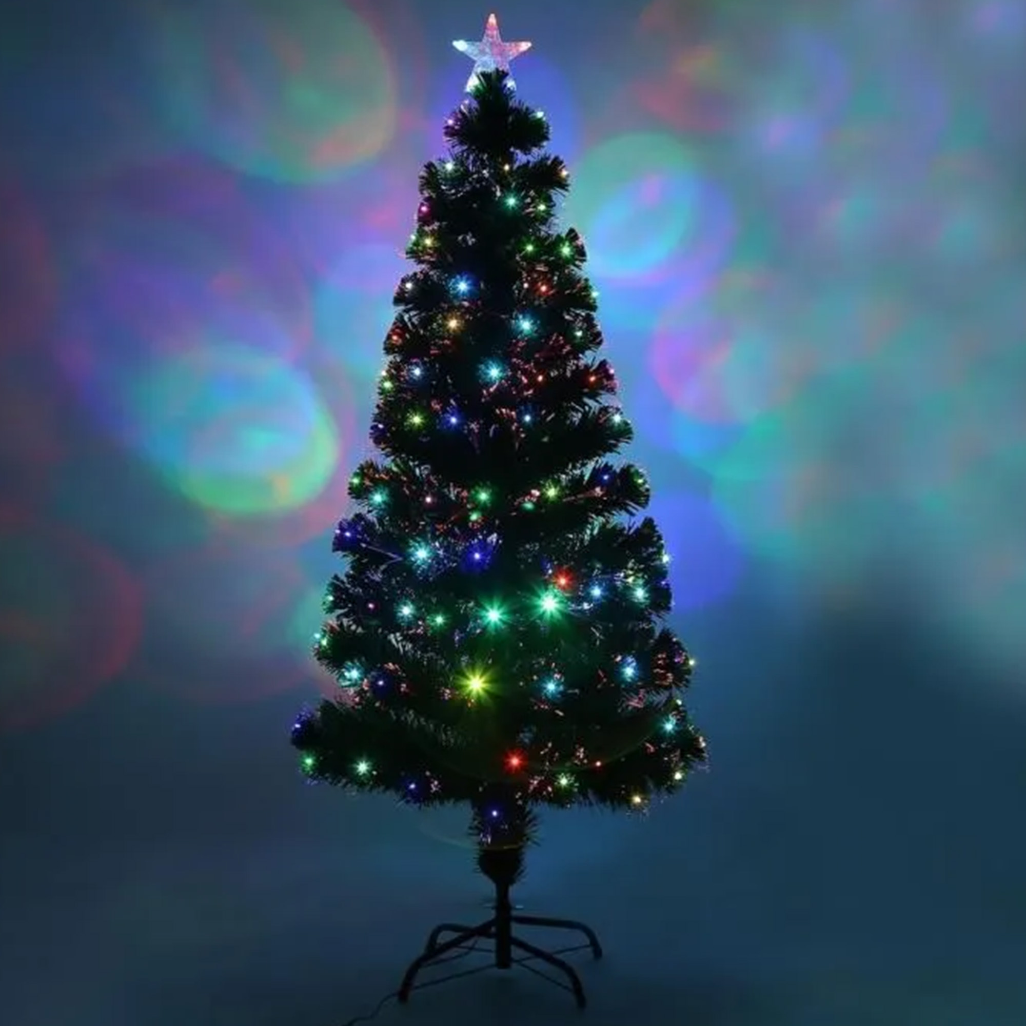 Un árbol de Navidad iluminado con luces de colores. Una estrella en la parte superior. El fondo tiene luces borrosas.