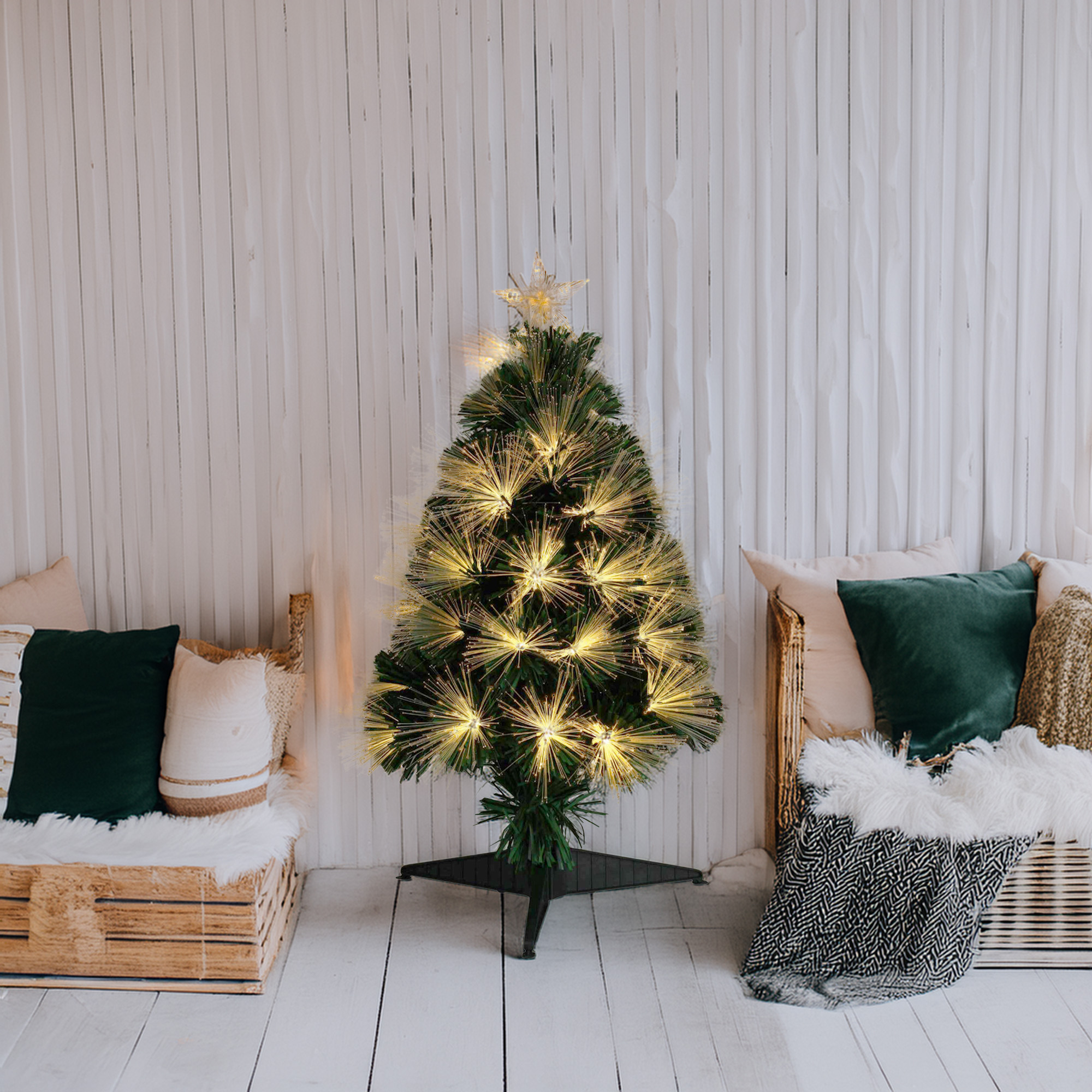 Un árbol de Navidad decorado con luces en una habitación. Alrededor, cojines y mantas.