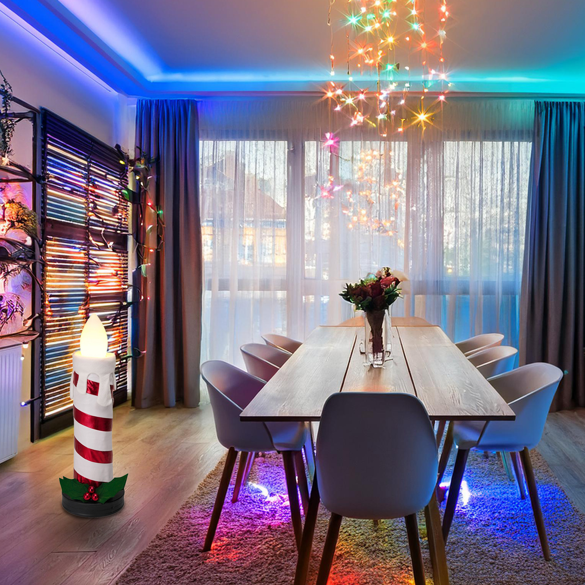 Una vela encendida con rayas rojas está en una habitación con mesa, sillas y luces coloridas.