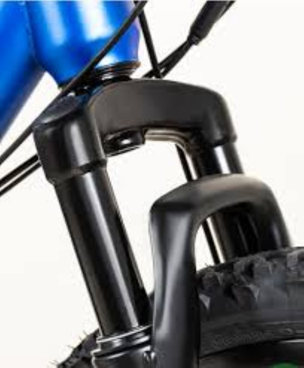 Primo piano di una forcella di bicicletta. Forcella nera con pneumatico visibile. Il telaio blu è in alto. Sono visibili anche i cavi.
