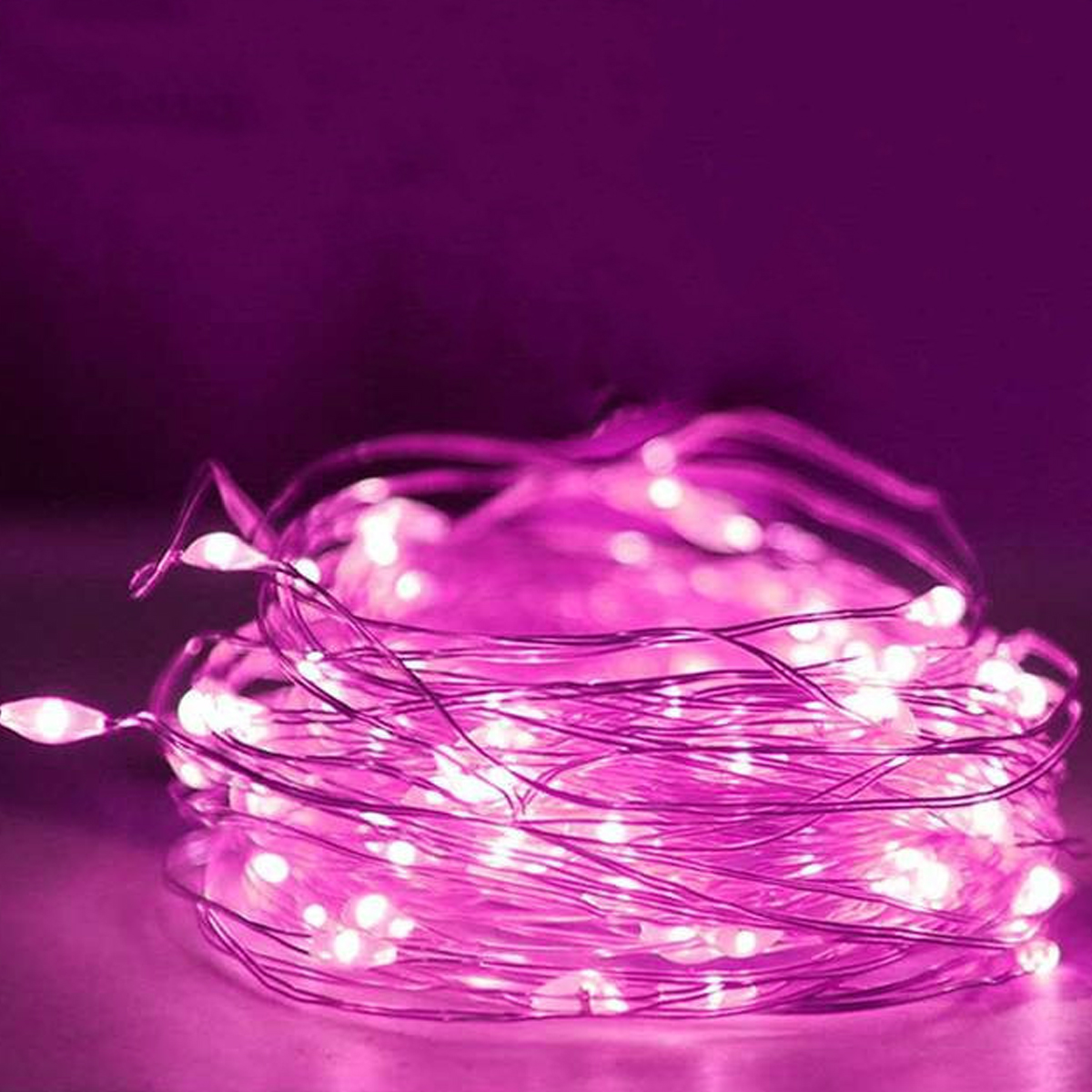 Nahaufnahme eines Bündels rosa Lichterketten. Die Lichter sind klein und hell und strahlen sanft. Sie liegen auf einer rosa Oberfläche.