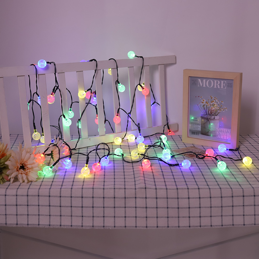 Catena di luci con lampadine colorate su un tavolo con cornice in legno bianco e cornice.