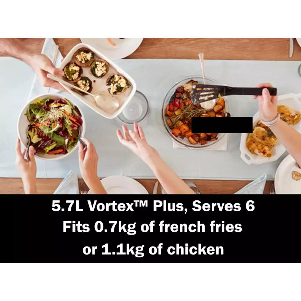 Stół nakryty do posiłku. Ręce sięgają po potrawy: sałatkę, faszerowane pieczarki, pieczone warzywa i smażonego kurczaka.