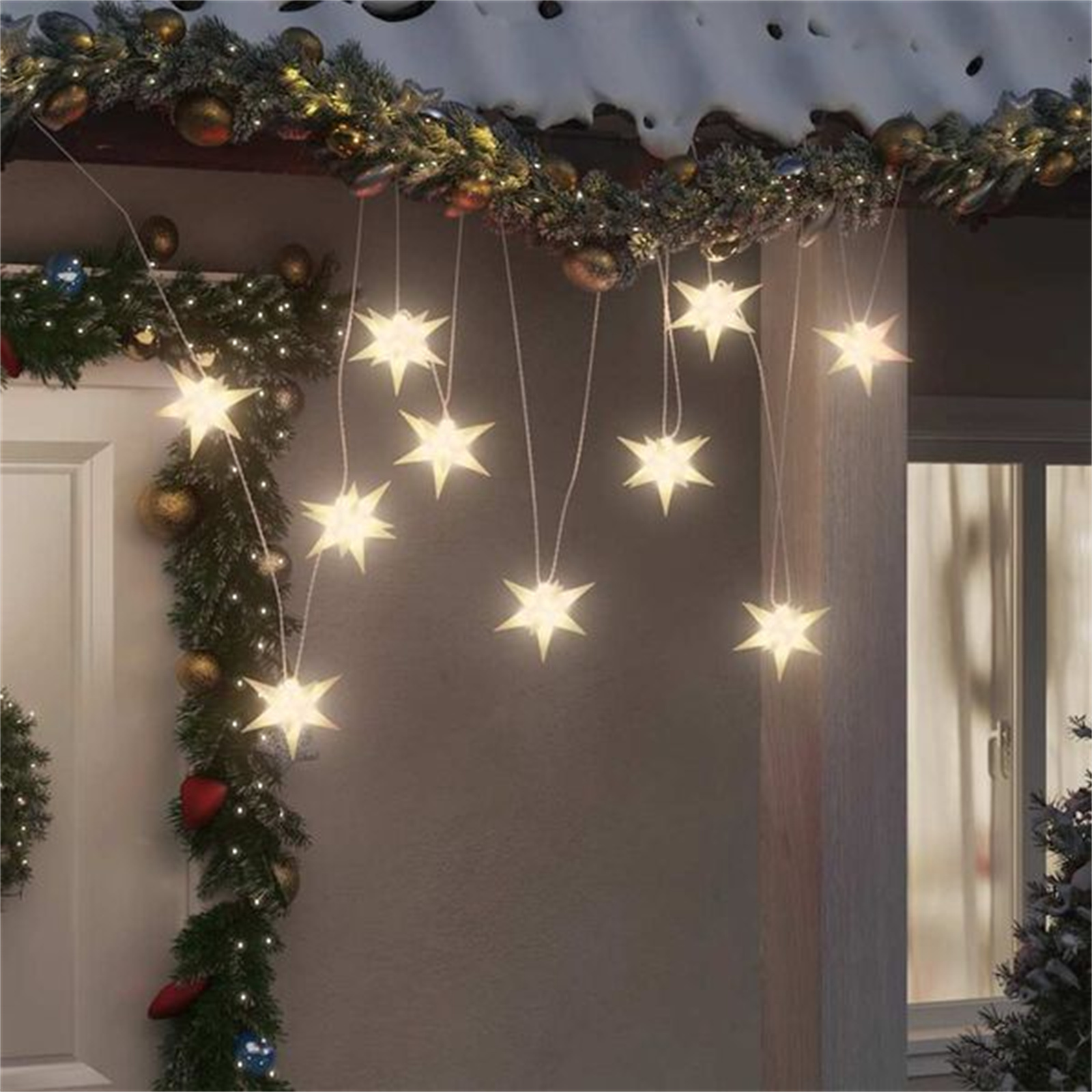 Weihnachtsdekoration im Freien. Sternförmige Lichter hängen von einem schneebedeckten Dachvorsprung über einer Tür.