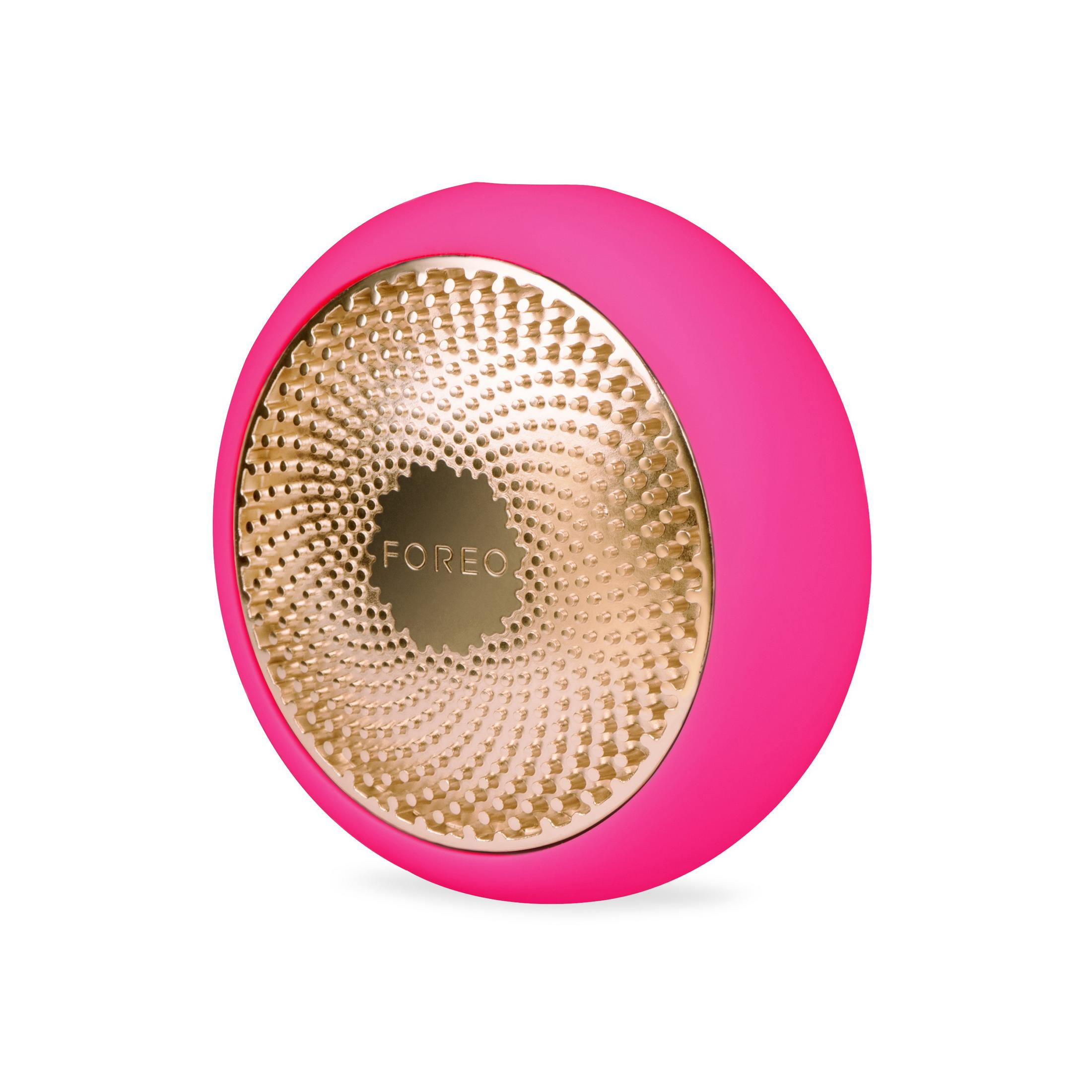 Beyaz zemin üzerinde pembe ve altın renkli bir Foreo cihazı. Foreo logosuyla yuvarlak şekle sahip.
