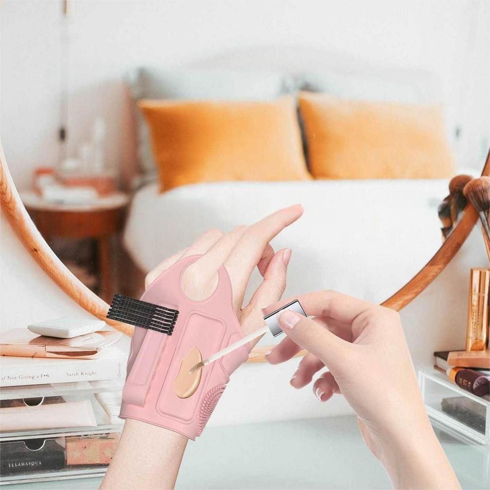Eine Hand trägt Make-up mit einem rosa Applikator auf. Im Hintergrund sind ein Spiegel und ein Schlafzimmer zu sehen.
