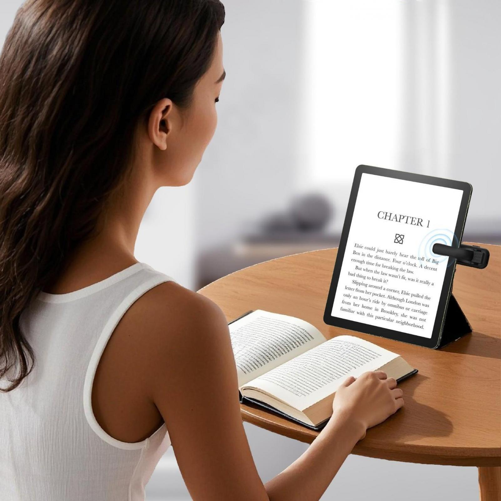 Frau, die ein Buch und einen E-Reader liest. Tisch. Weißes Oberteil. Kapitel 1 ist auf dem Reader sichtbar.