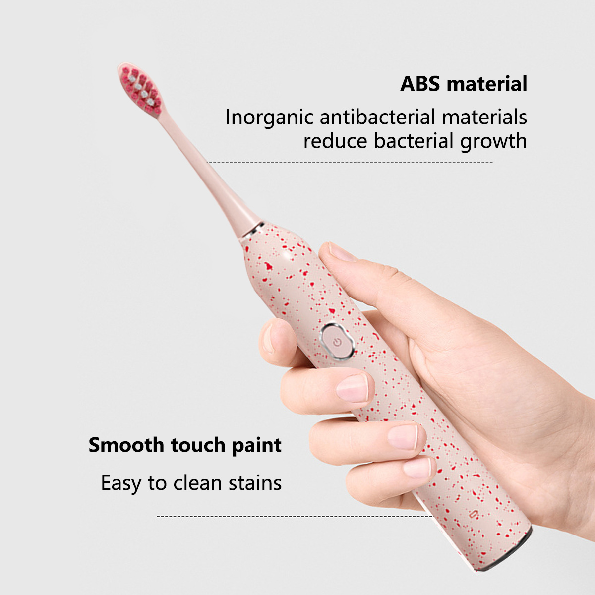 Eine Hand hält eine rosa elektrische Zahnbürste mit roten Sprenkeln. Text sagt 'ABS-Material' und 'Sanfte Haptik'.
