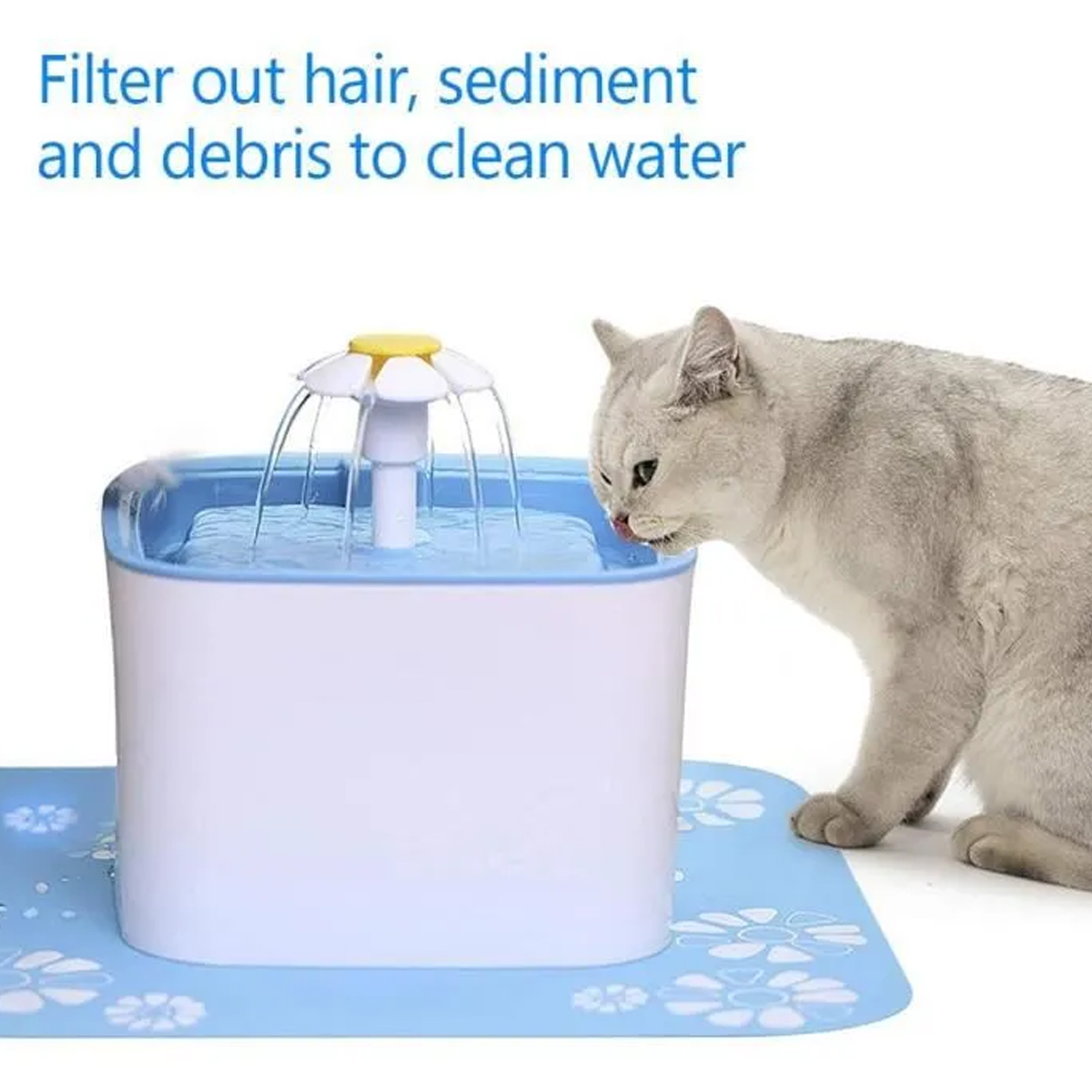 Eine graue Katze trinkt aus einem Wasserbrunnen. Der Brunnen ist weiß und blau, und das Wasser fließt aus einer blütenförmigen Spitze.