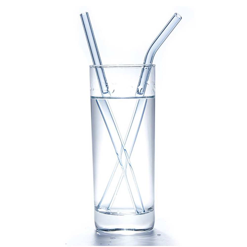 Ein klares Glas Wasser mit zwei Glasstrohhalmen. Die Strohhalme sind transparent und angewinkelt. Weißer Hintergrund.
