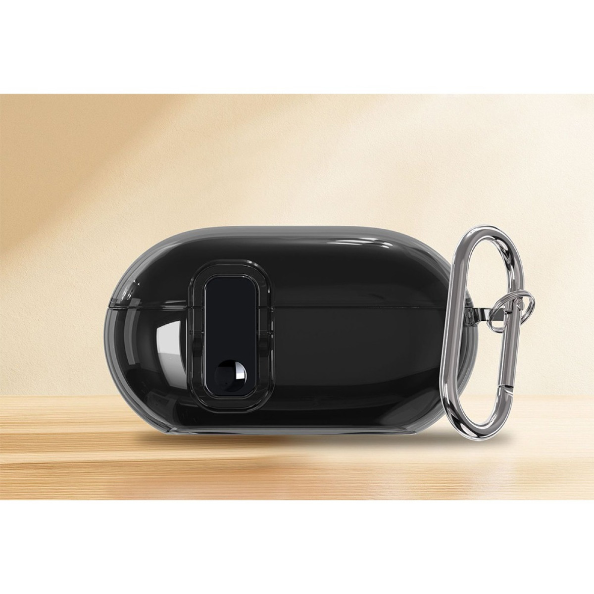 A black, oval-shaped earbud case with a silver carabiner clip, placed on a wooden surface against a beige backdrop.